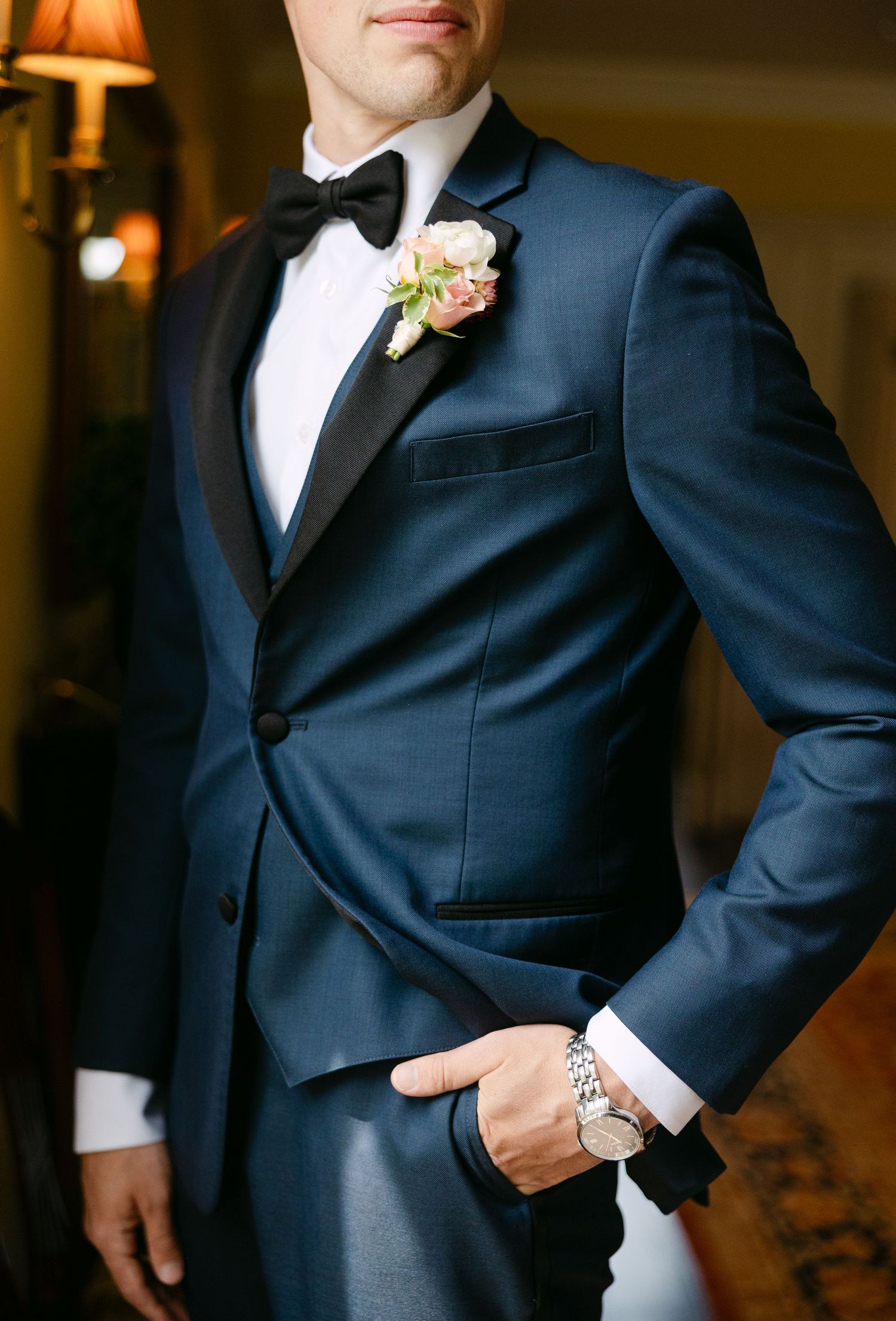 Formal wedding party members in black tuxedos and suits standing together before the ceremony.
