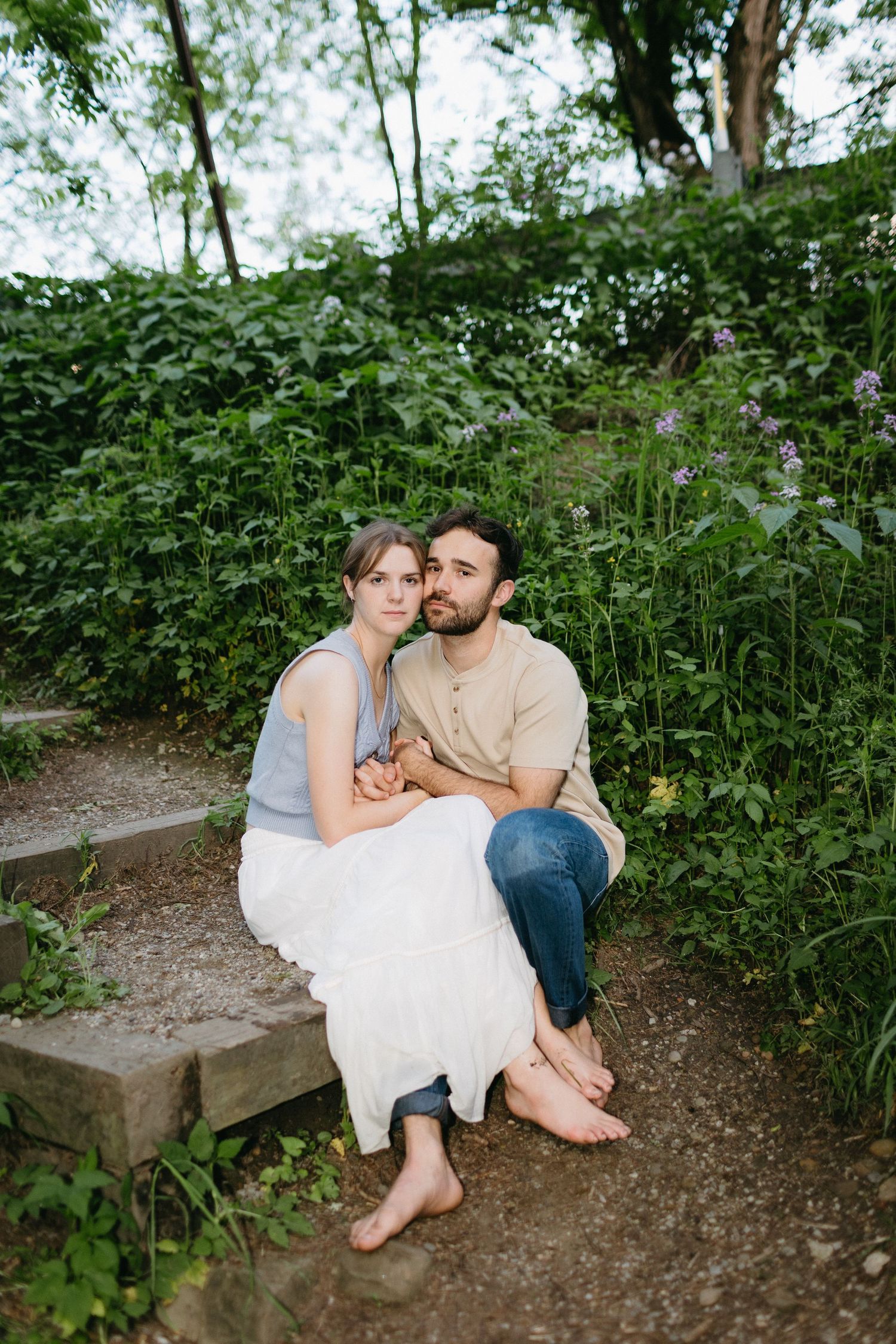 Intimate portrait of couple sitting on stone steps in wooded area.