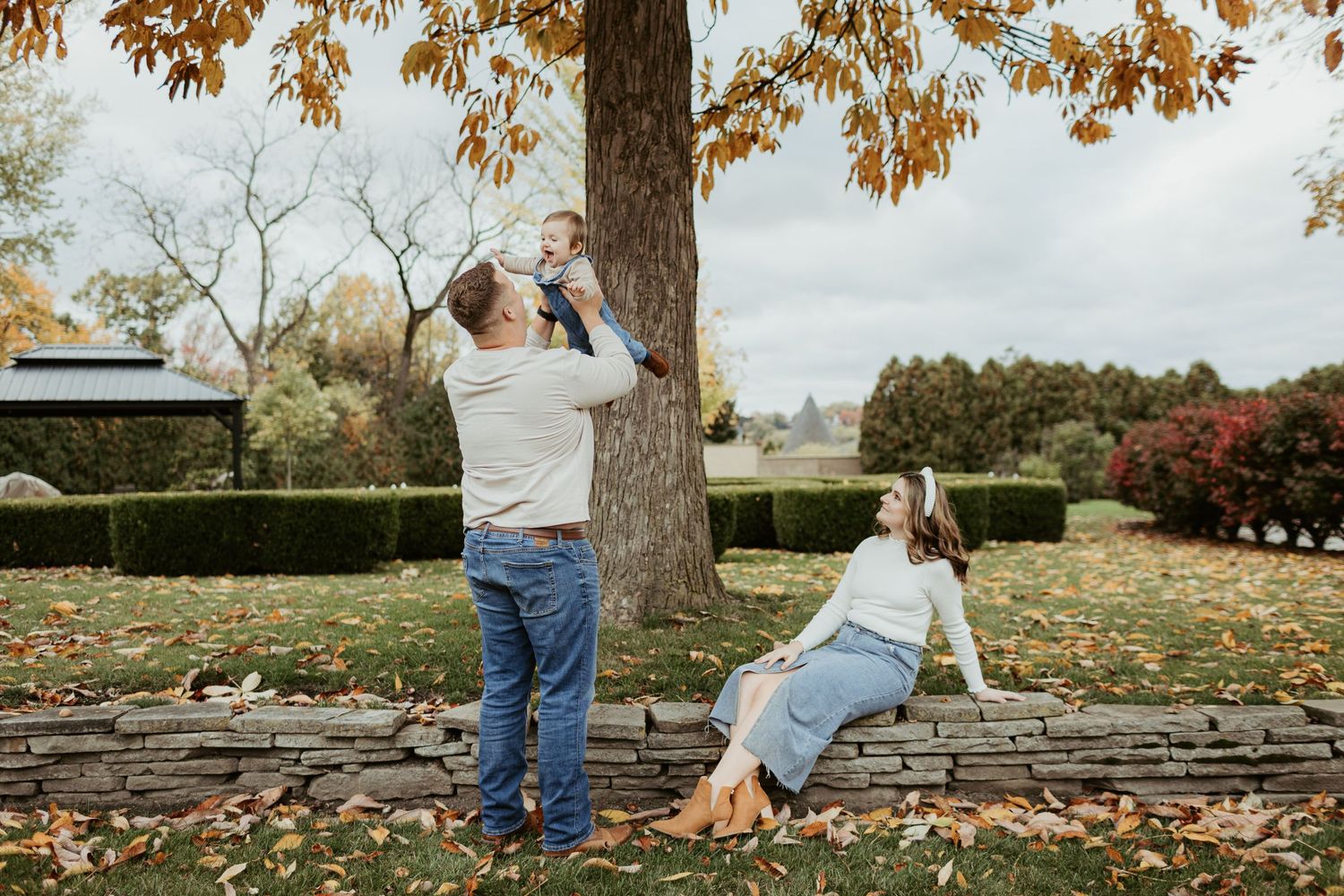 Two people enjoying a casual autumn photoshoot in a park with fallen leaves and warm colors.