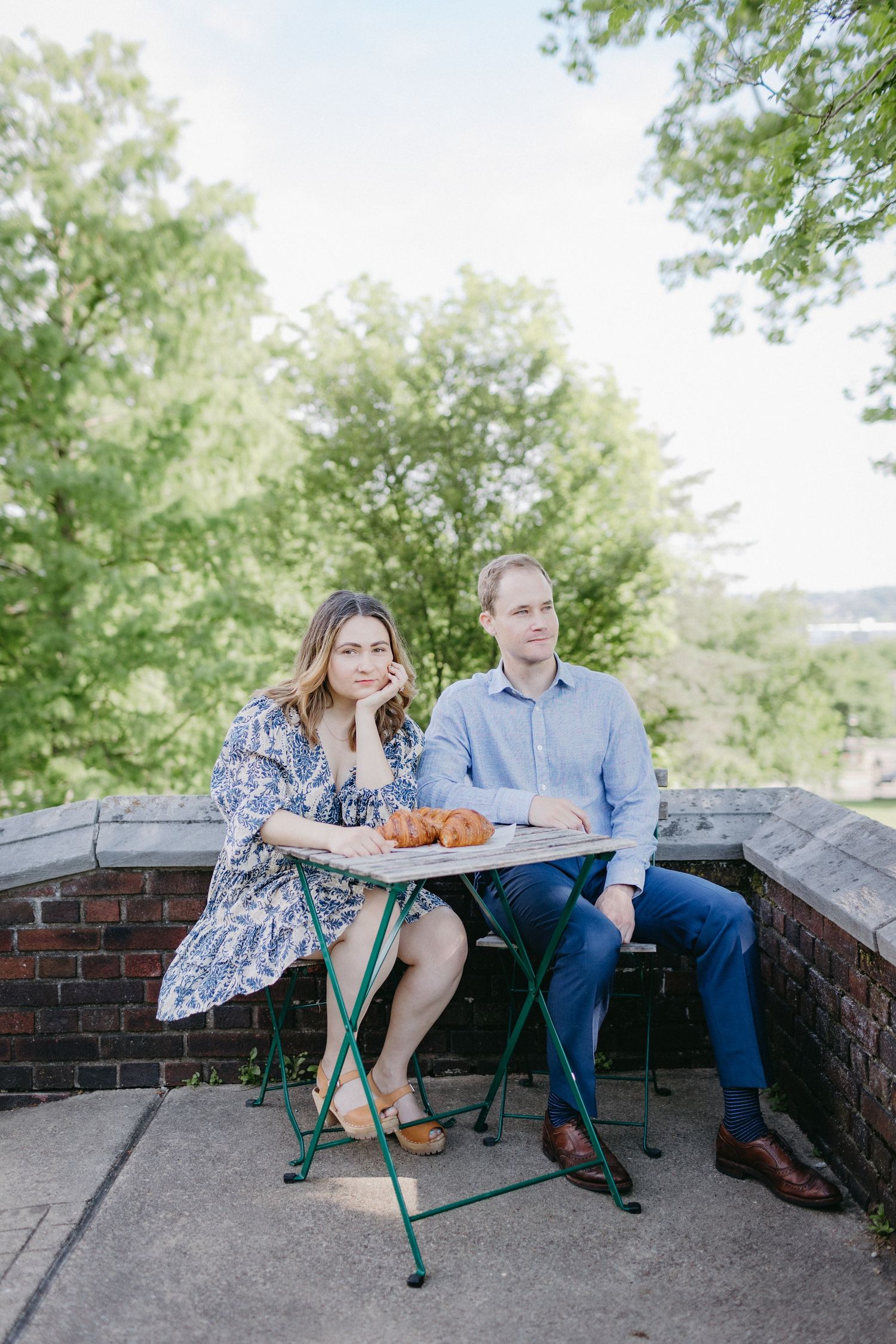 Couple sitting at outdoor cafe table with food on sunny day.