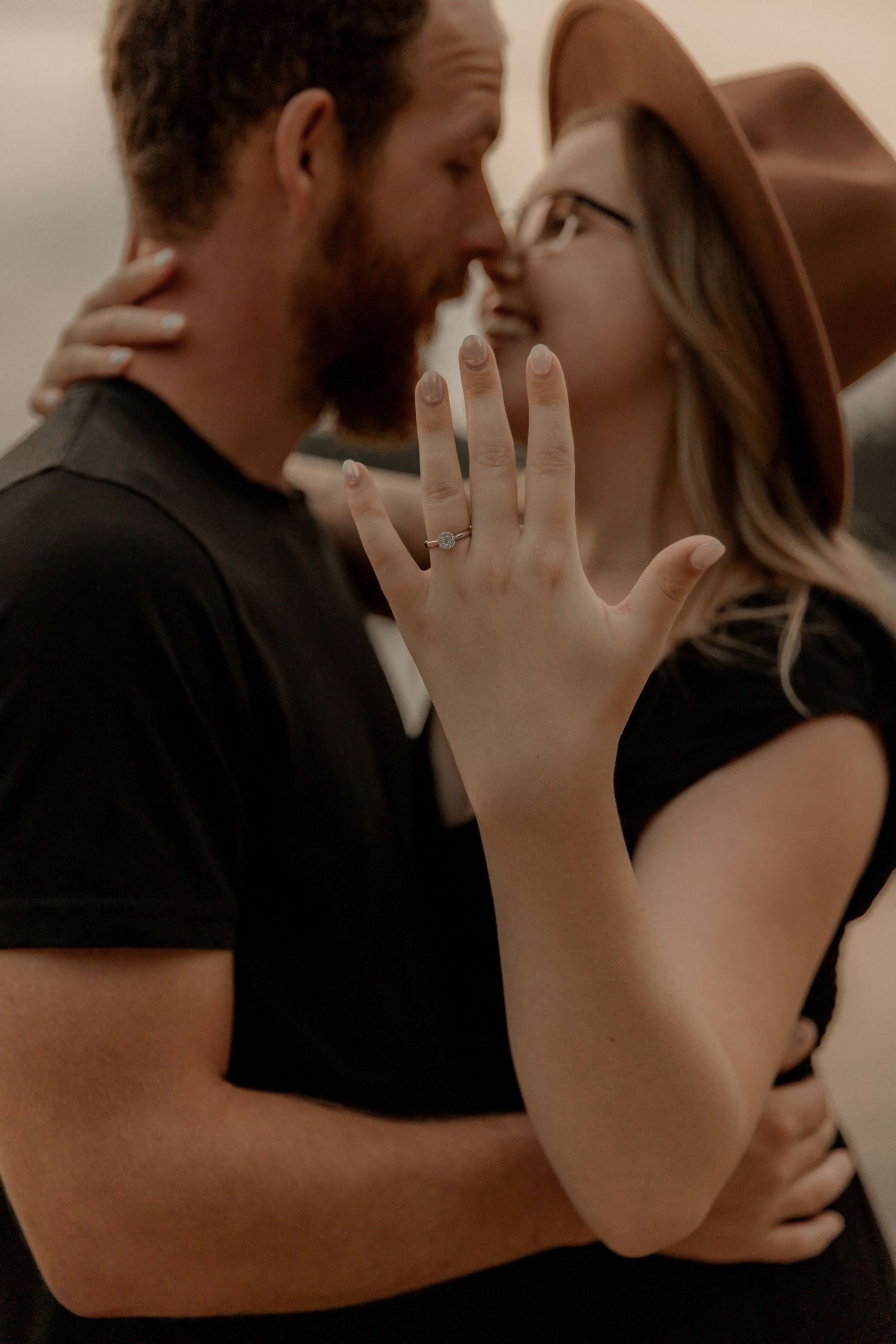 Couple sharing an intimate moment together while showing off a new engagement ring.
