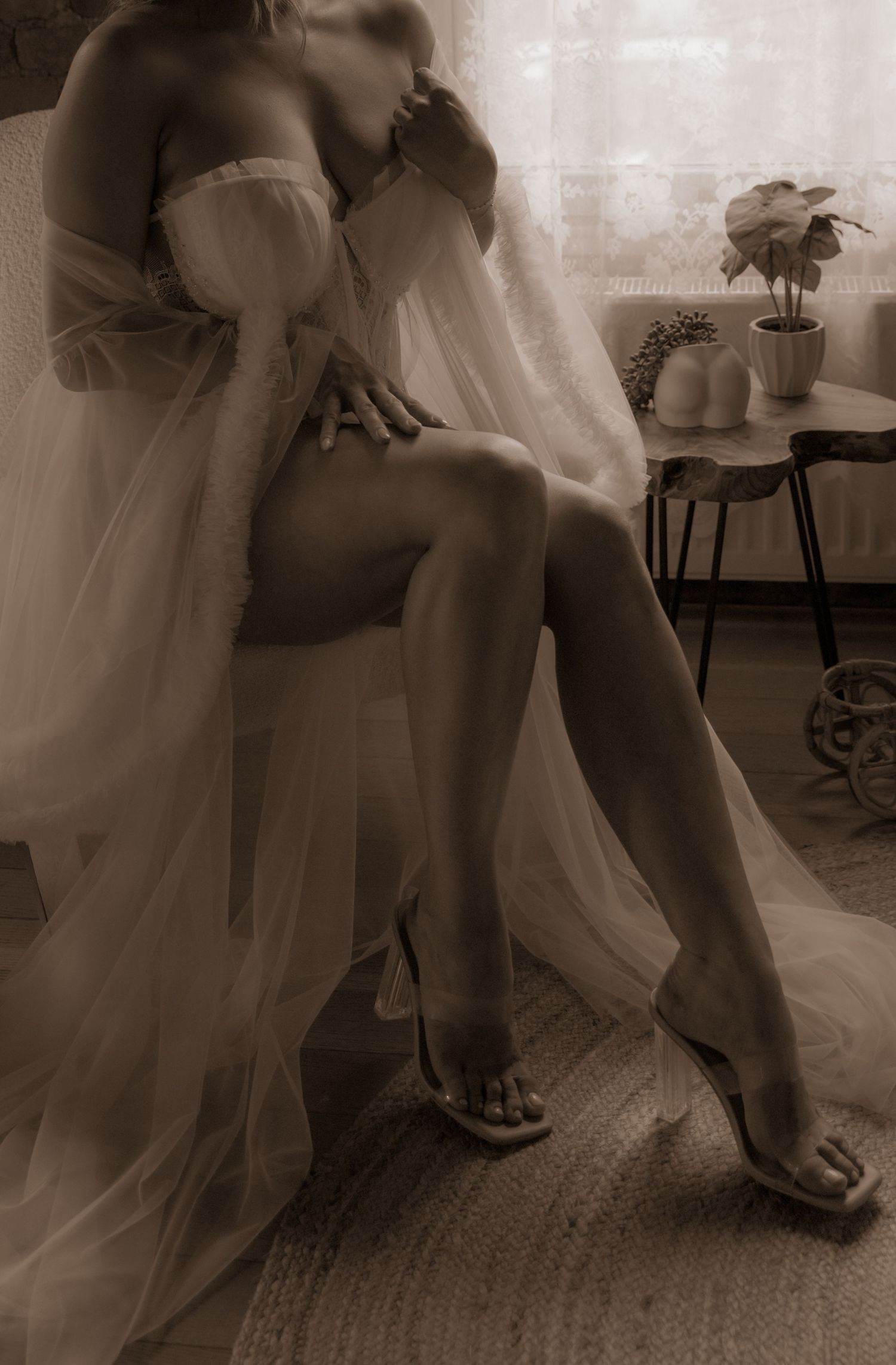 Moody sepia boudoir image featuring soft fabric draping and natural window light.