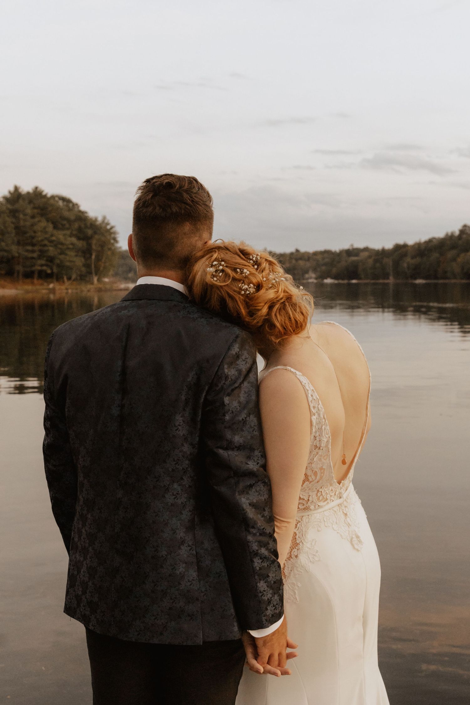 A couple shares an intimate moment while overlooking a serene lake at dusk.
