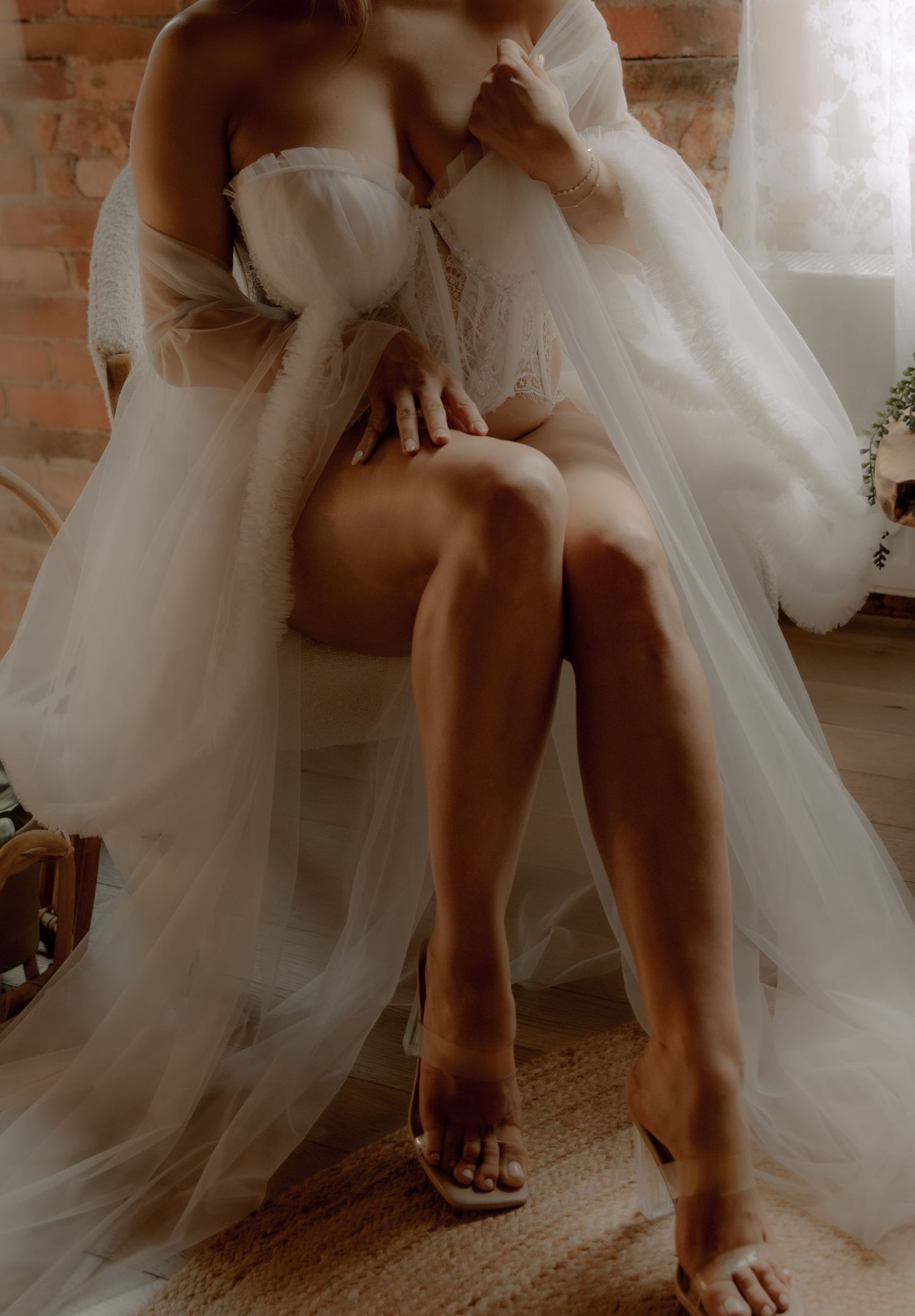 Warm-toned intimate portrait with flowing tulle dress against exposed brick and natural light.
