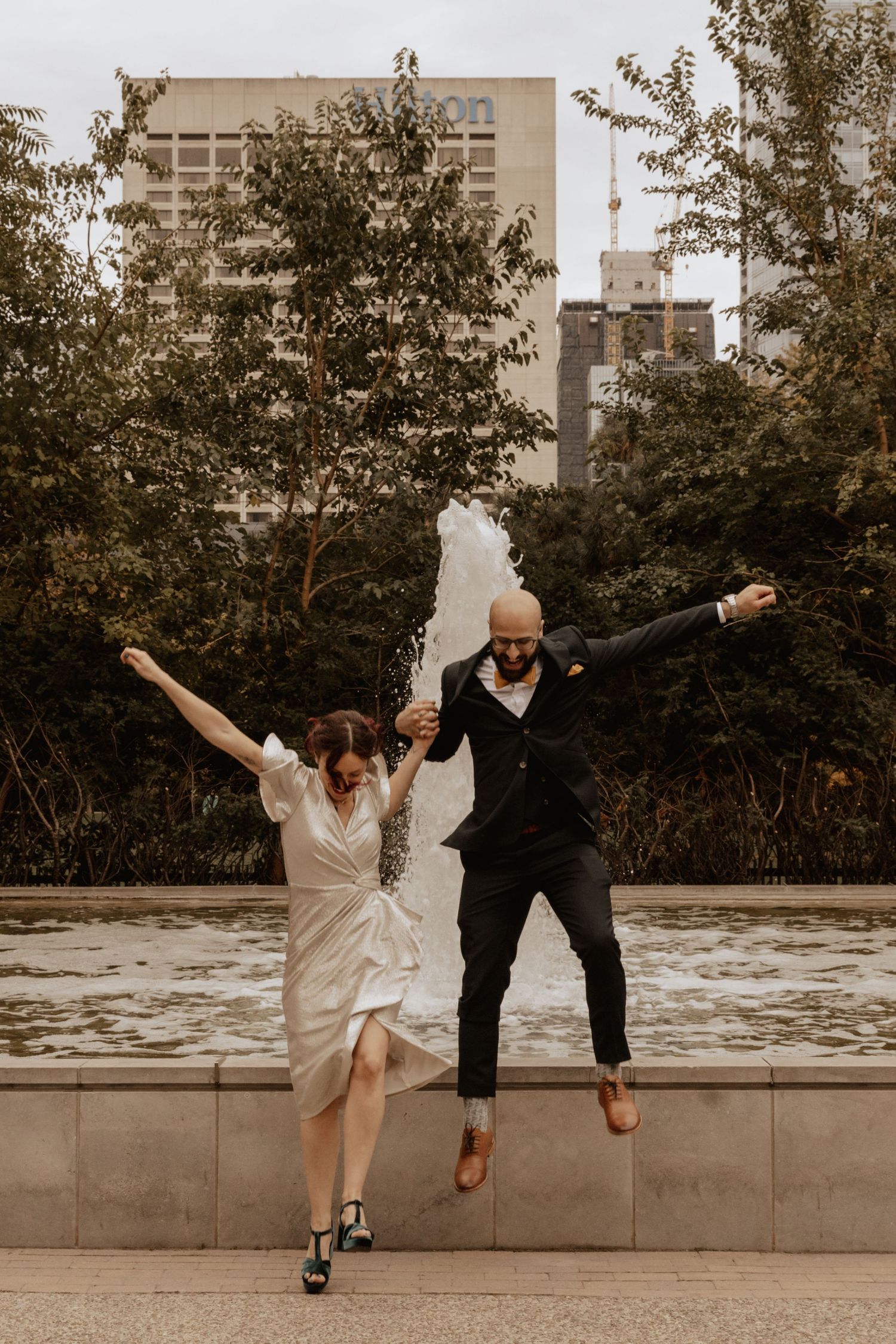 A joyful couple leaps into the air during an urban wedding photoshoot.