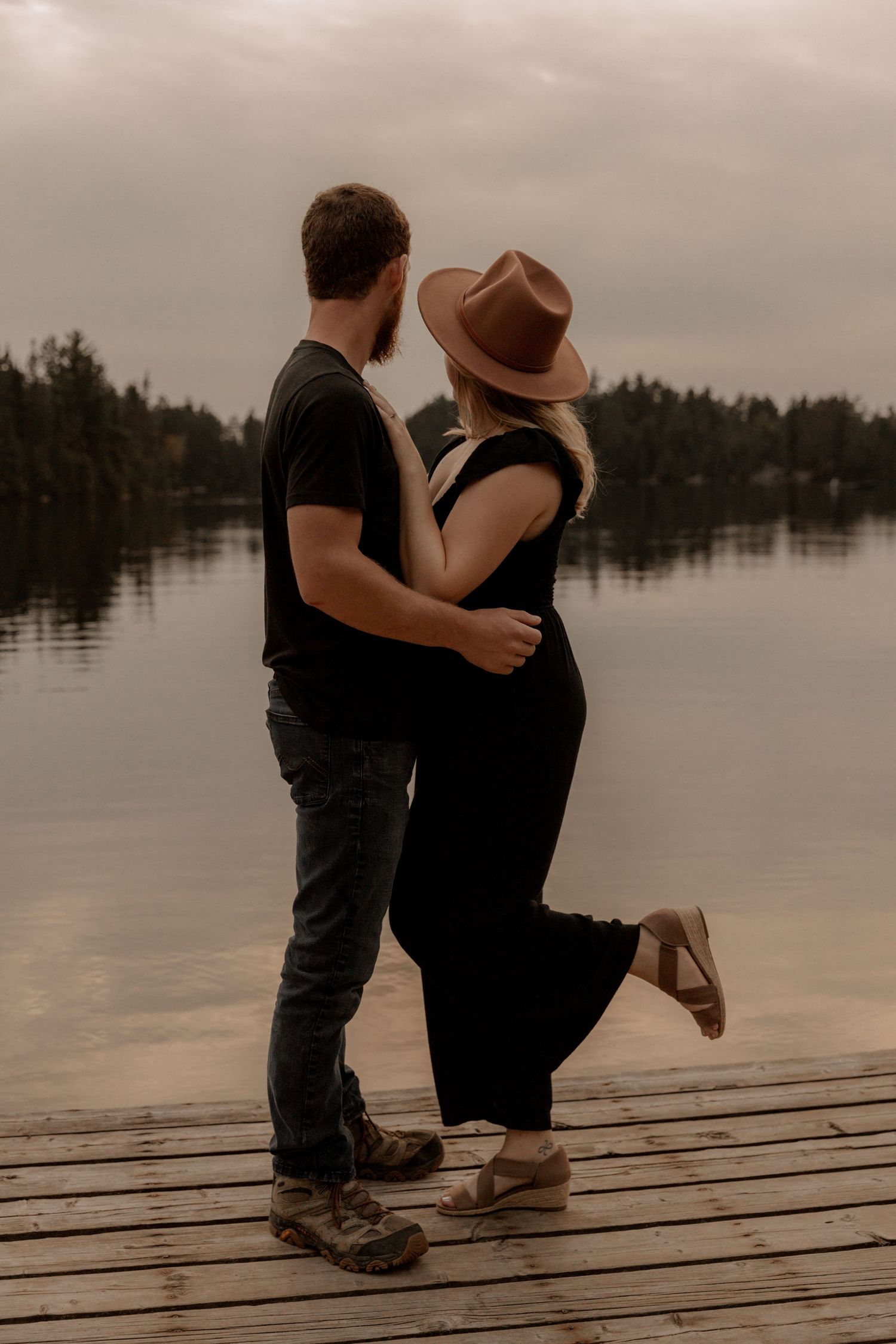 Romantic couple embracing on a wooden dock by a serene lake.