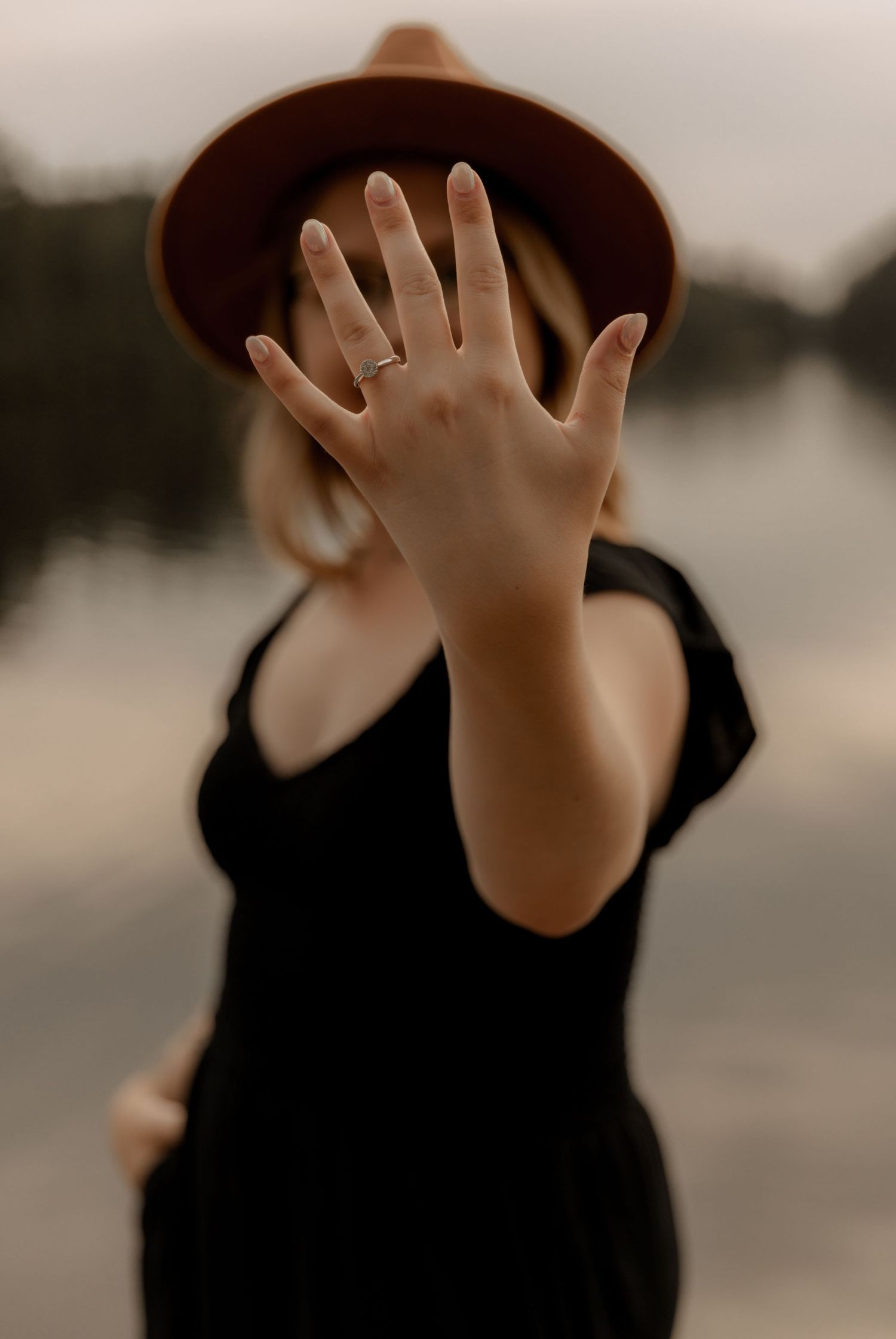 A hand reaches up toward the camera against a blurry lake background.
