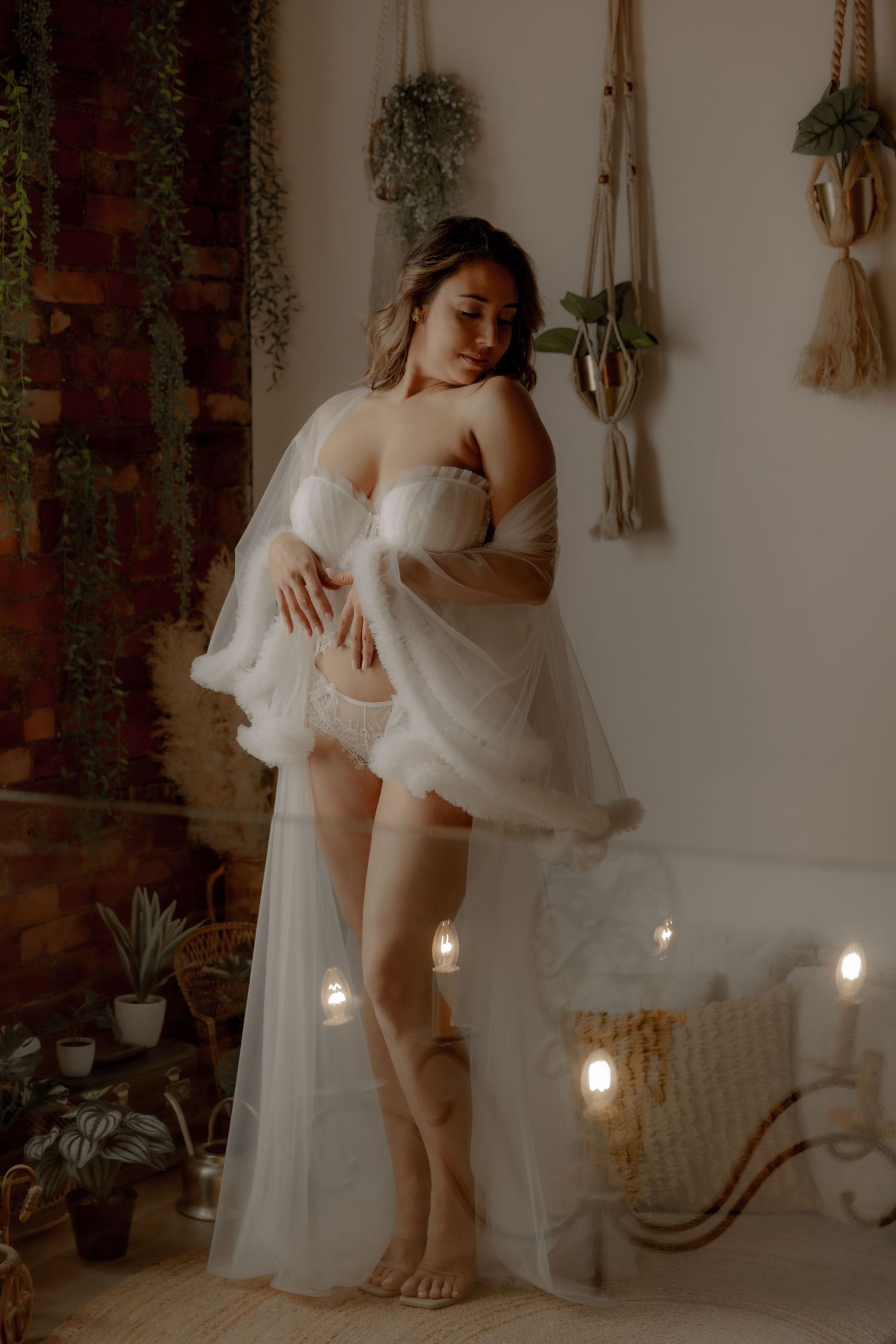 Ethereal boudoir scene featuring flowing white fabric and glowing candles against exposed brick walls.