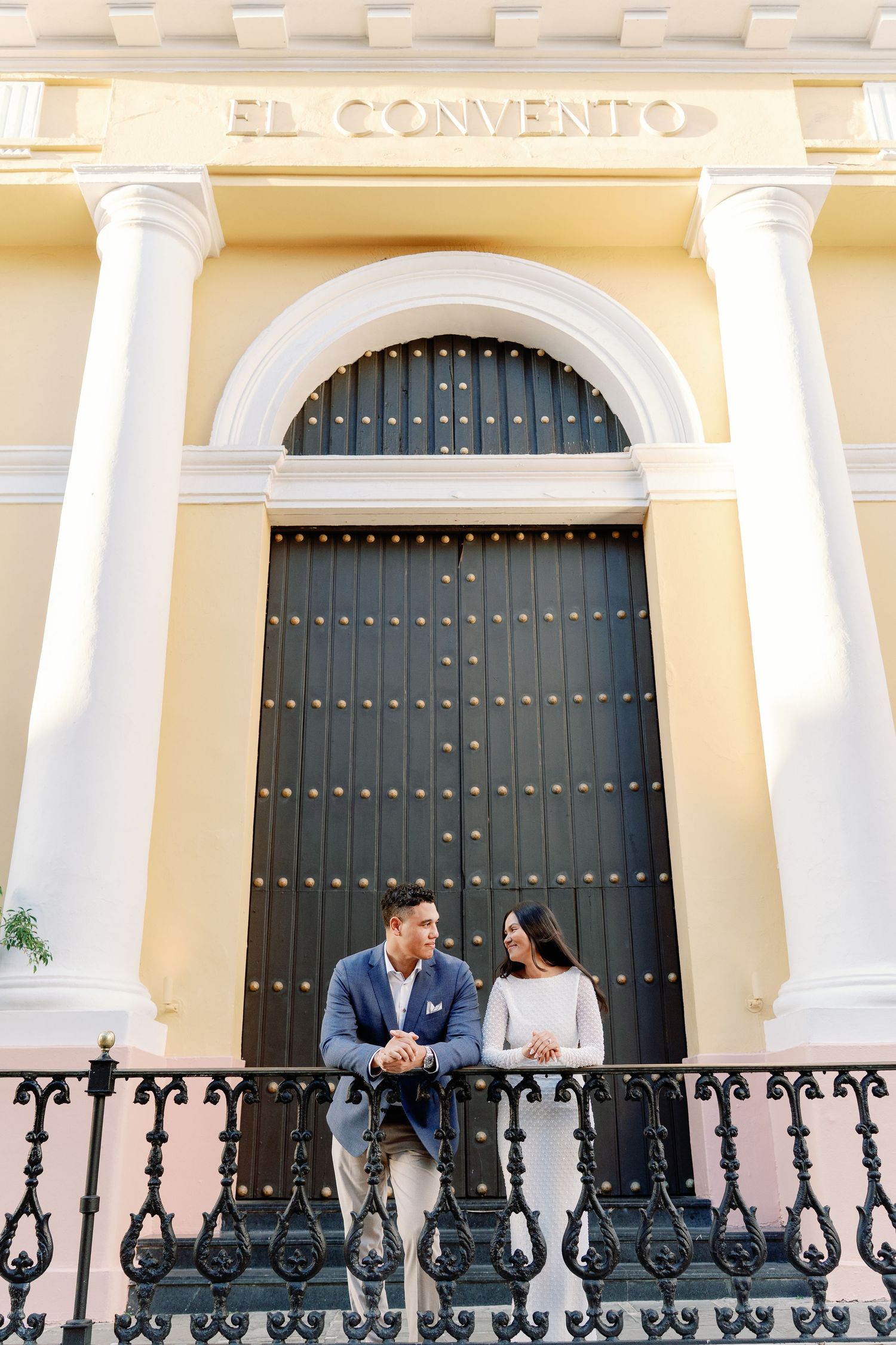 Couple smiling at each other on ornate balcony of El Convento hotel in Old San Juan, Puerto Rico.