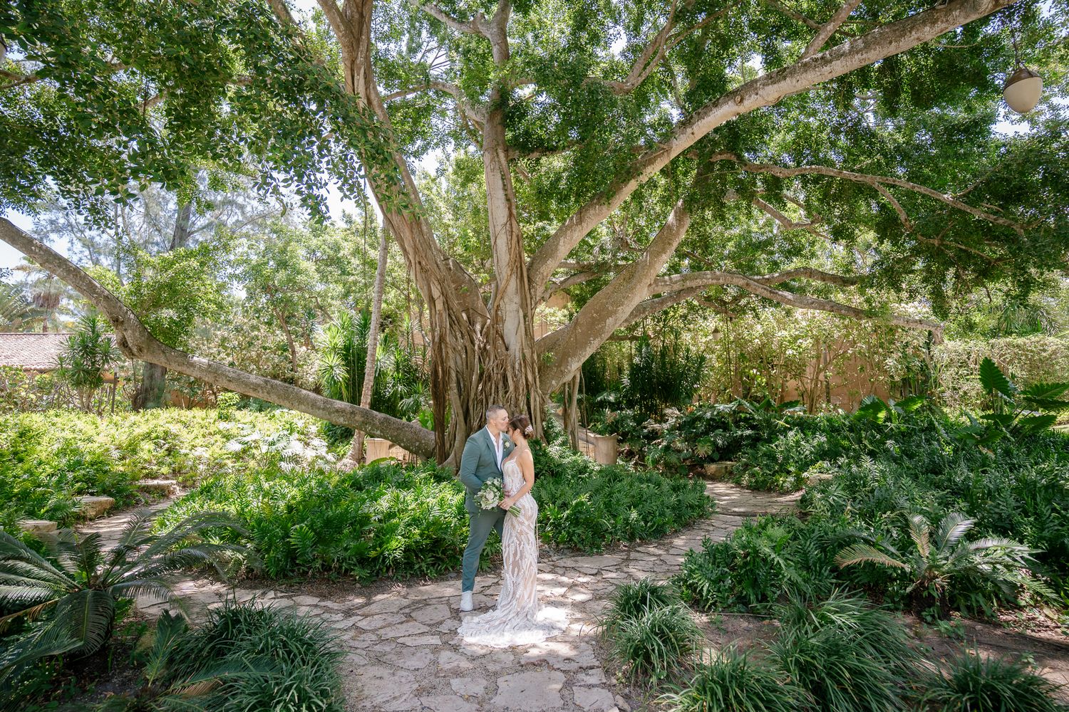 A tranquil walking path winds through lush gardens and mature trees in a serene botanical setting.