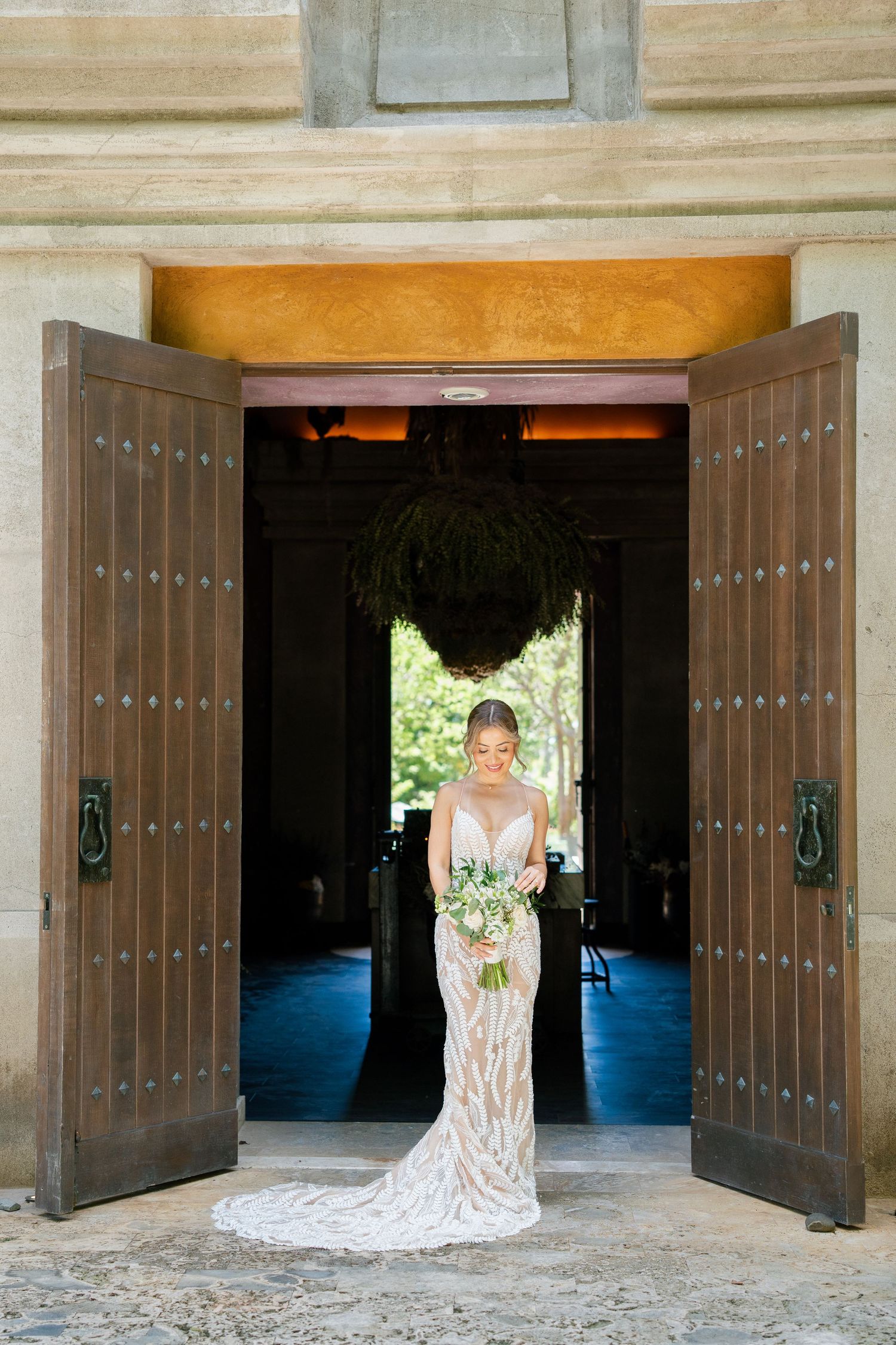 Wedding portraits framed by grand wooden doors and stone archways in elegant venue.