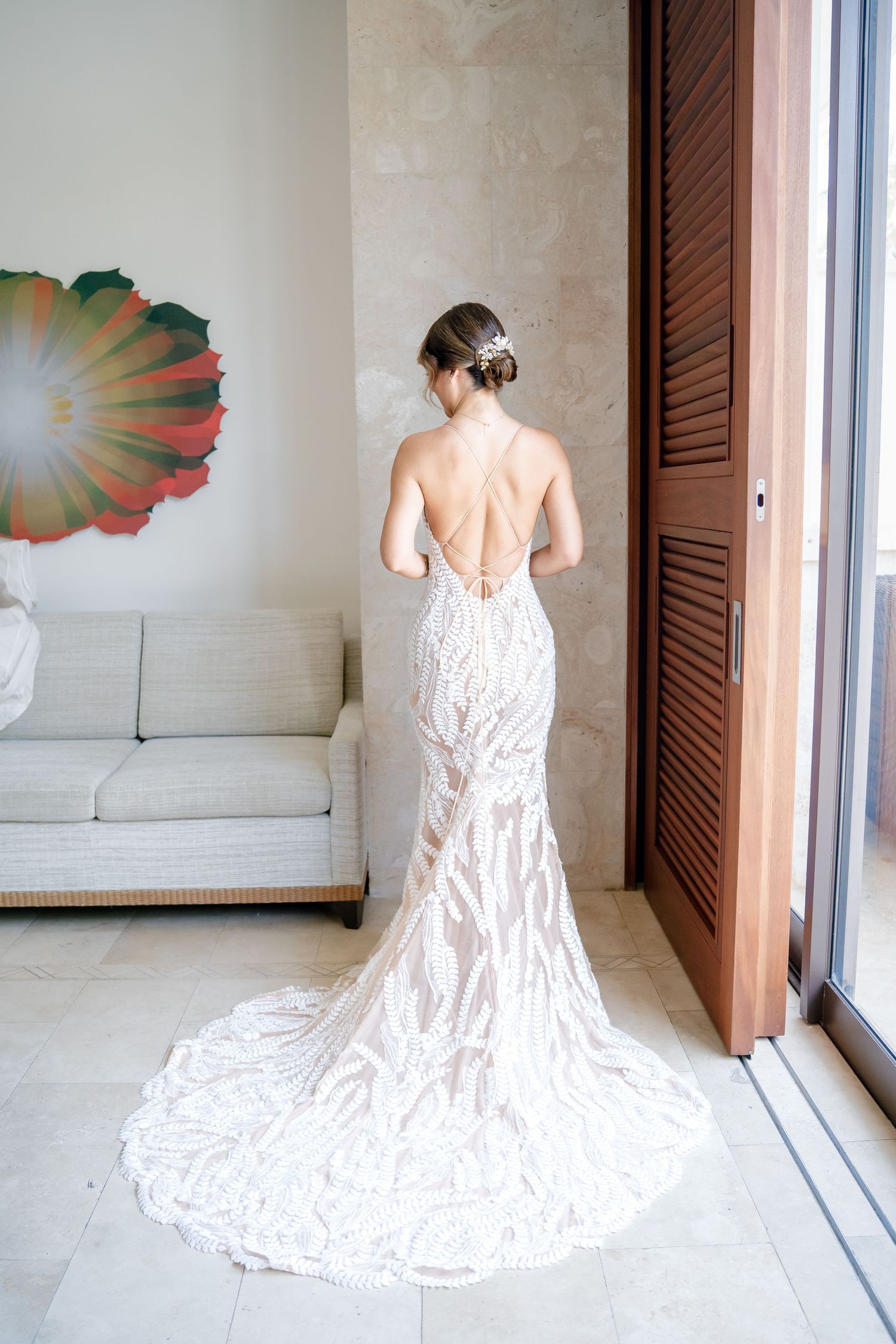 Back view of a stunning white lace wedding gown with dramatic train in modern interior.
