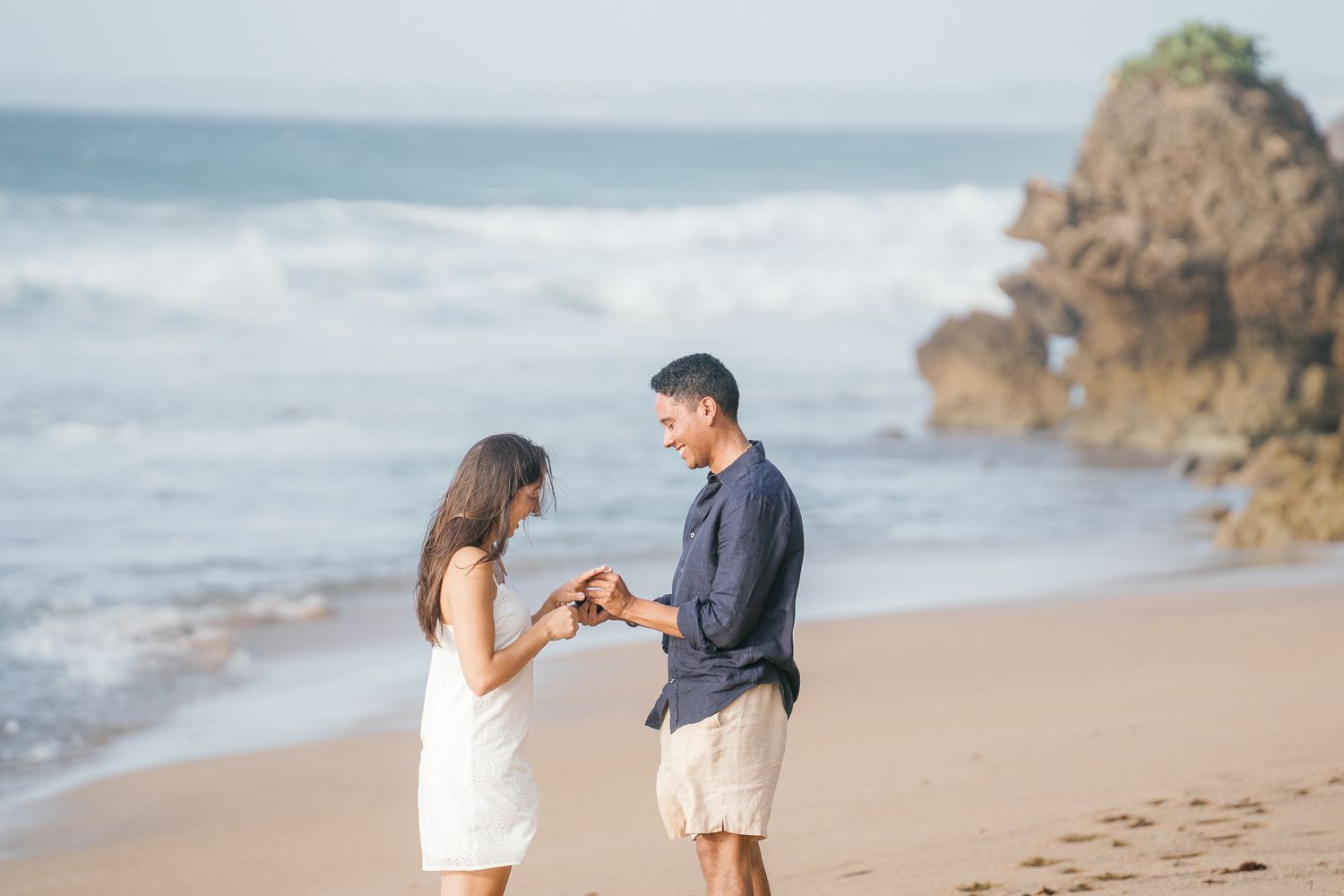 Romantic beach proposal sequence showing couple getting engaged on sandy shoreline with ocean waves in background.