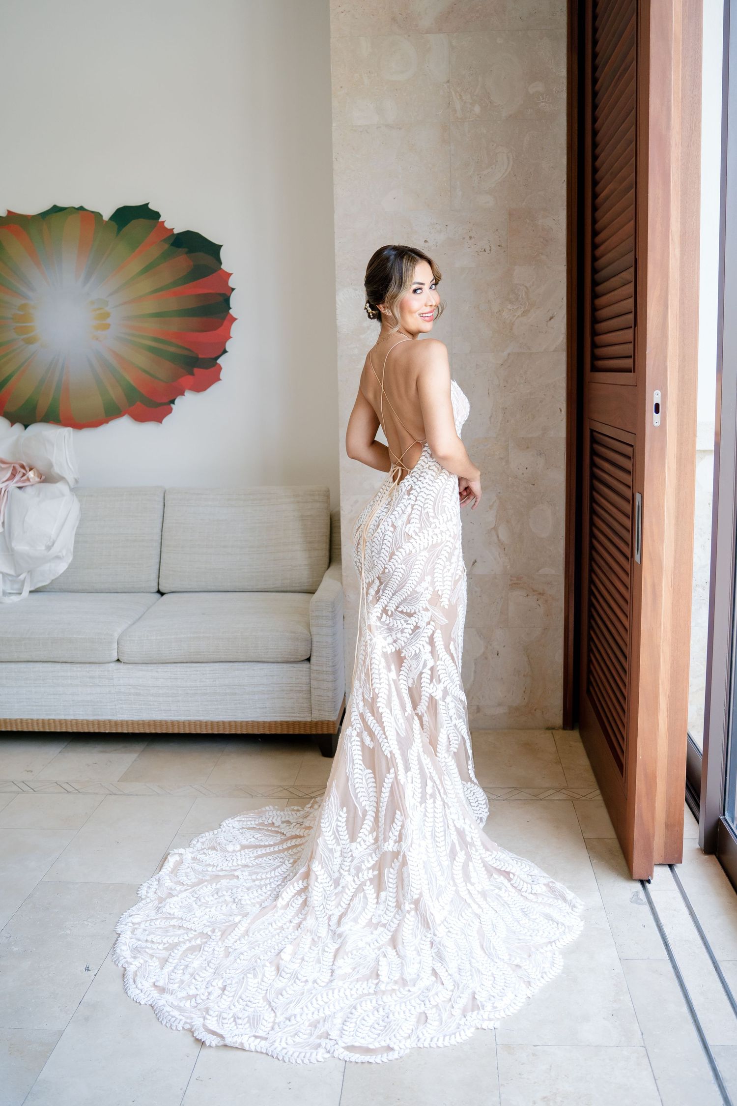 Wedding dress with intricate lace pattern and long train shown in sequence against neutral backdrop.