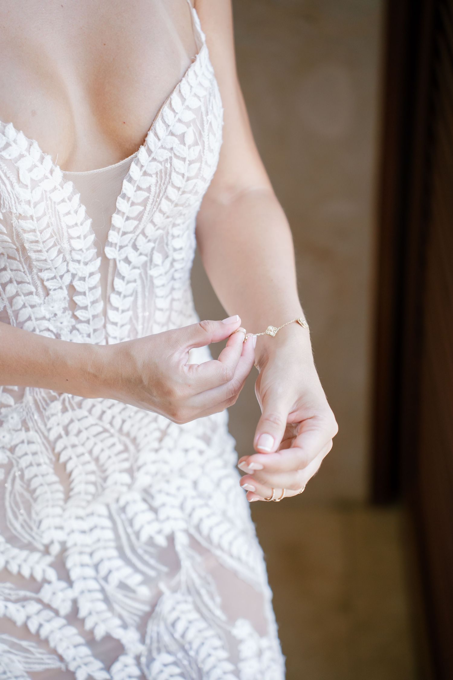 Close up detail of intricate white beaded wedding dress bodice and delicate hands.