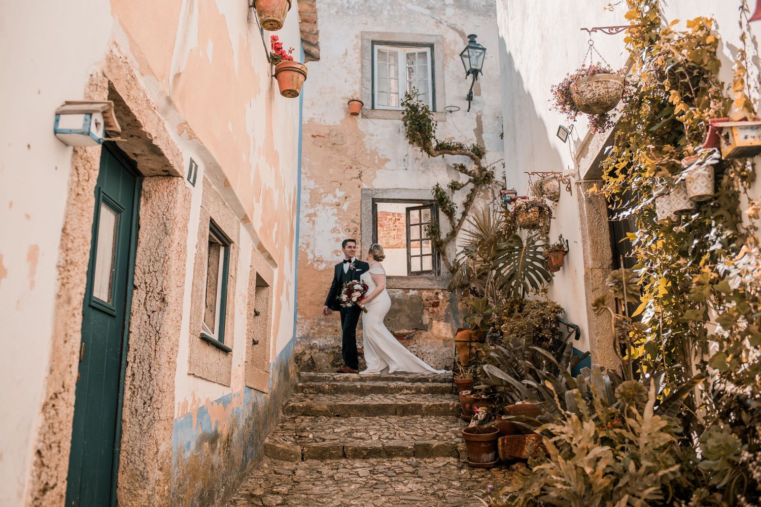 Bride and groom embracing in the historic streets of Óbidos during a destination wedding in Portugal.