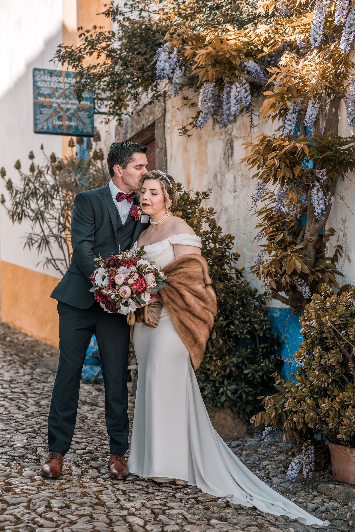 Intimate destination wedding in Óbidos, Portugal, with bride and groom walking through the medieval streets at sunset.