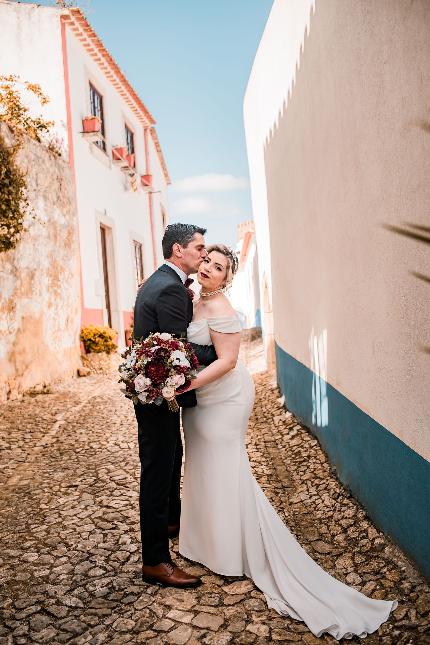 Bride and groom embracing in the historic streets of Óbidos during a destination wedding in Portugal.