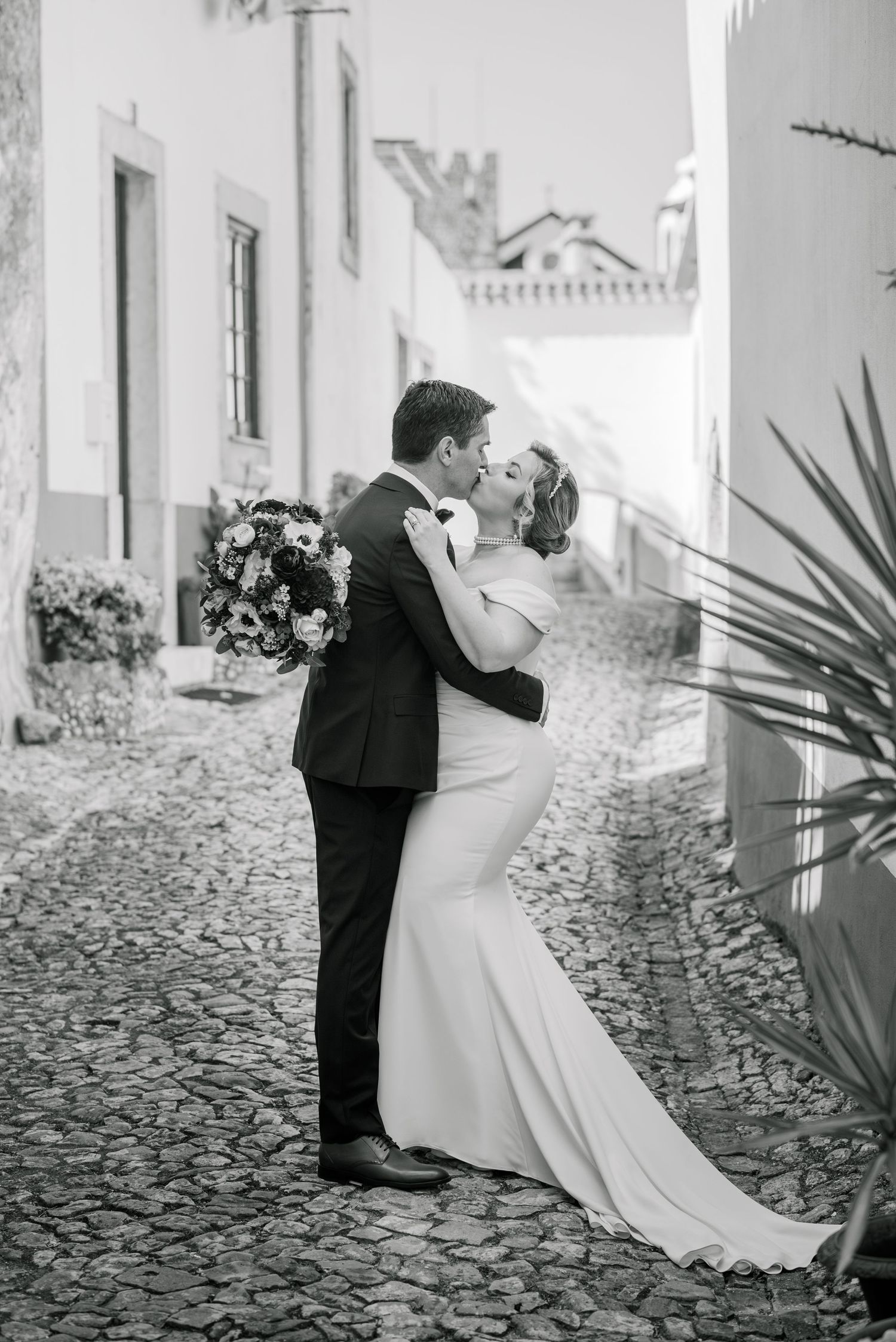 Bride and groom embracing in the historic streets of Óbidos during a destination wedding in Portugal.