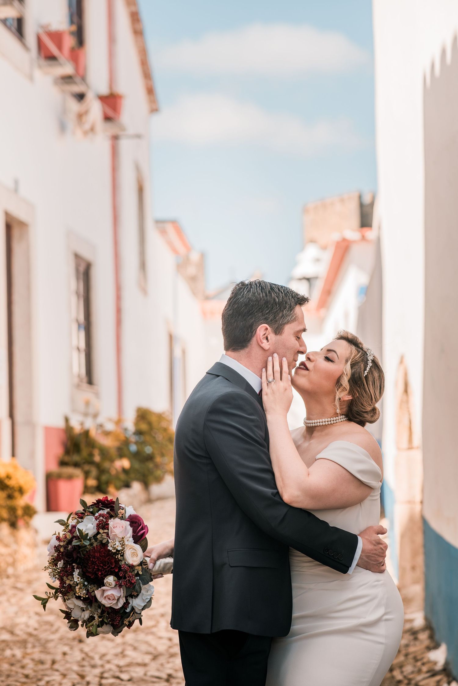Bride and groom embracing in the historic streets of Óbidos during a destination wedding in Portugal.
