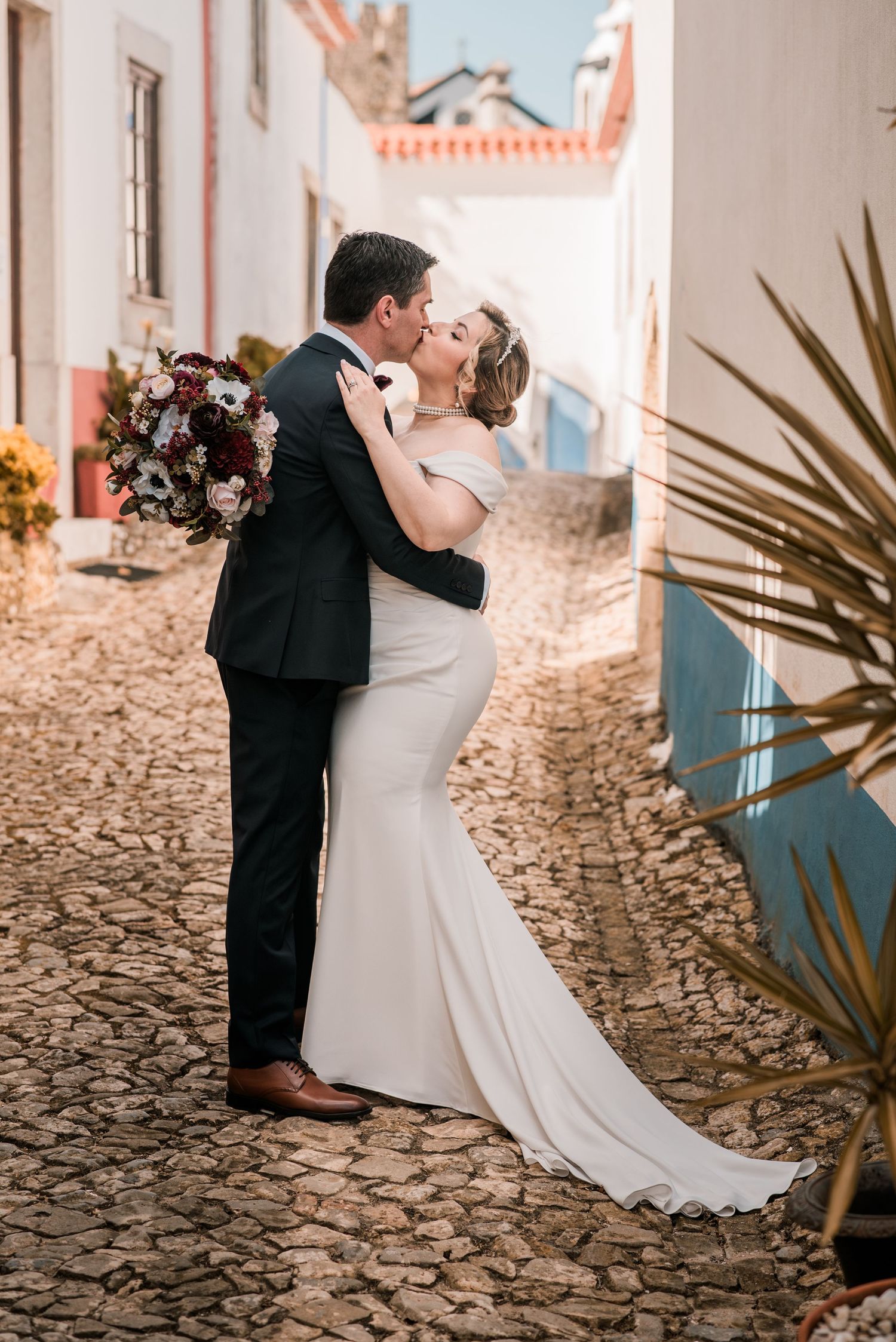 Bride and groom embracing in the historic streets of Óbidos during a destination wedding in Portugal.