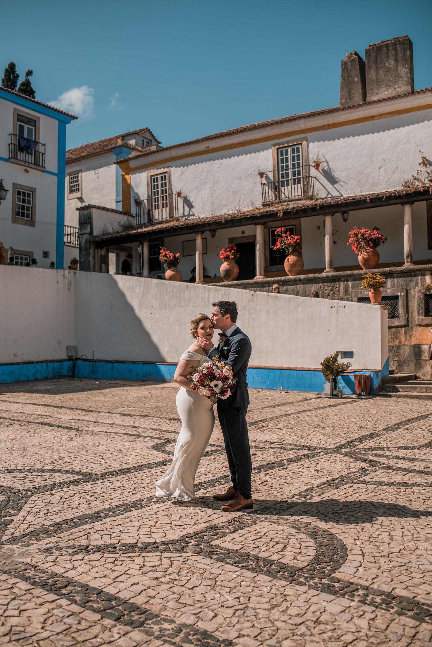 Bride and groom embracing in the historic streets of Óbidos during a destination wedding in Portugal.