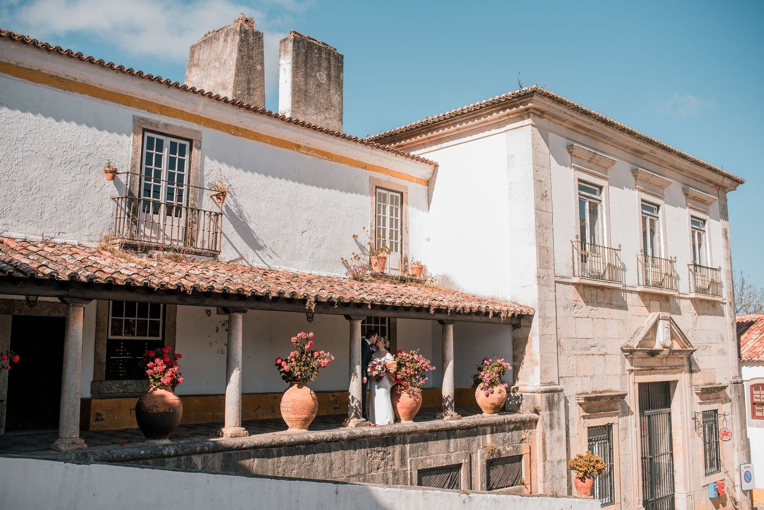 Intimate destination wedding in Óbidos, Portugal, with bride and groom walking through the medieval streets at sunset.
