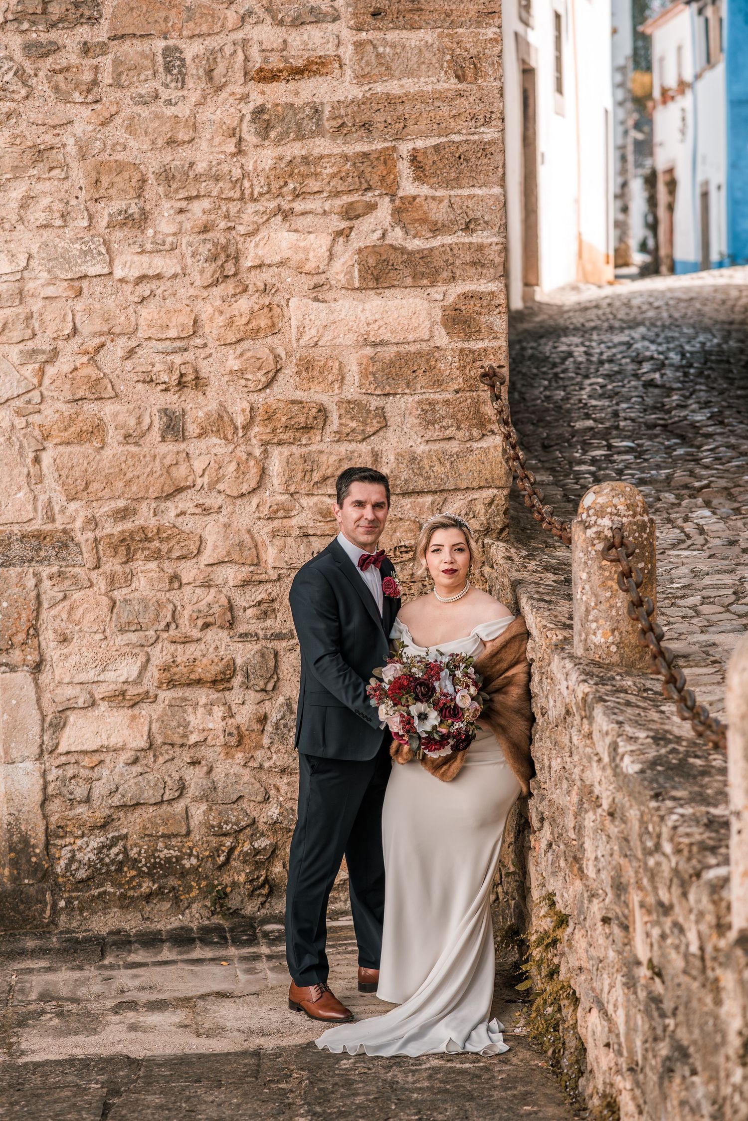 Intimate destination wedding in Óbidos, Portugal, with bride and groom walking through the medieval streets at sunset.