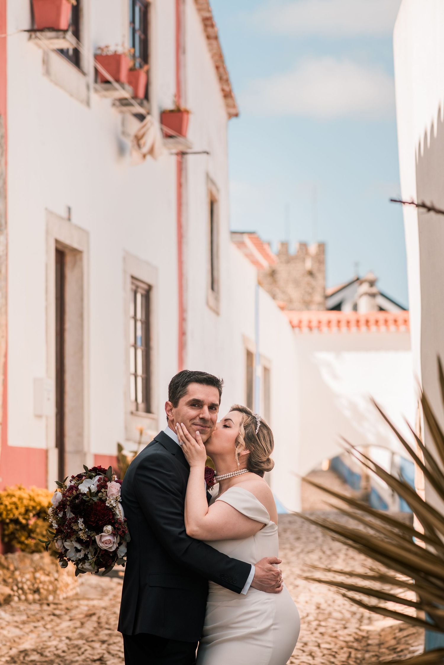 Bride and groom embracing in the historic streets of Óbidos during a destination wedding in Portugal.