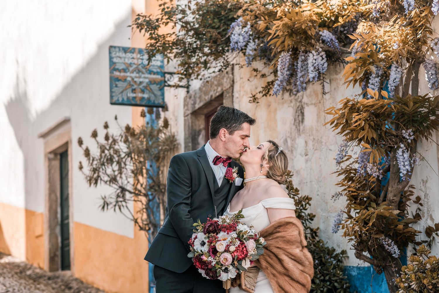 Intimate destination wedding in Óbidos, Portugal, with bride and groom walking through the medieval streets at sunset.