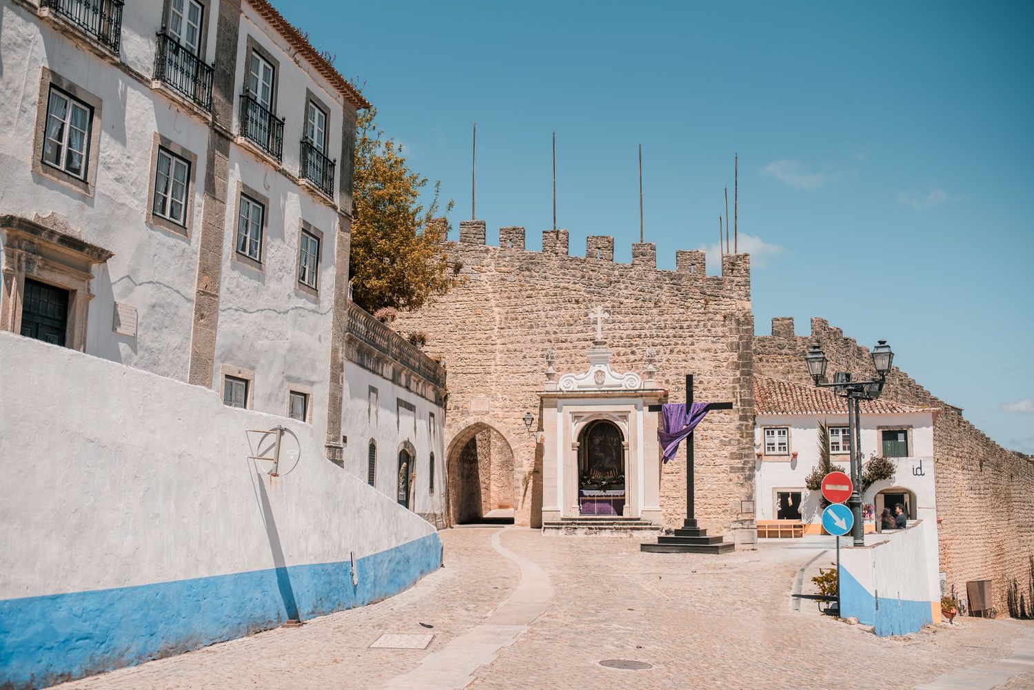 Intimate destination wedding in Óbidos, Portugal, with bride and groom walking through the medieval streets at sunset.