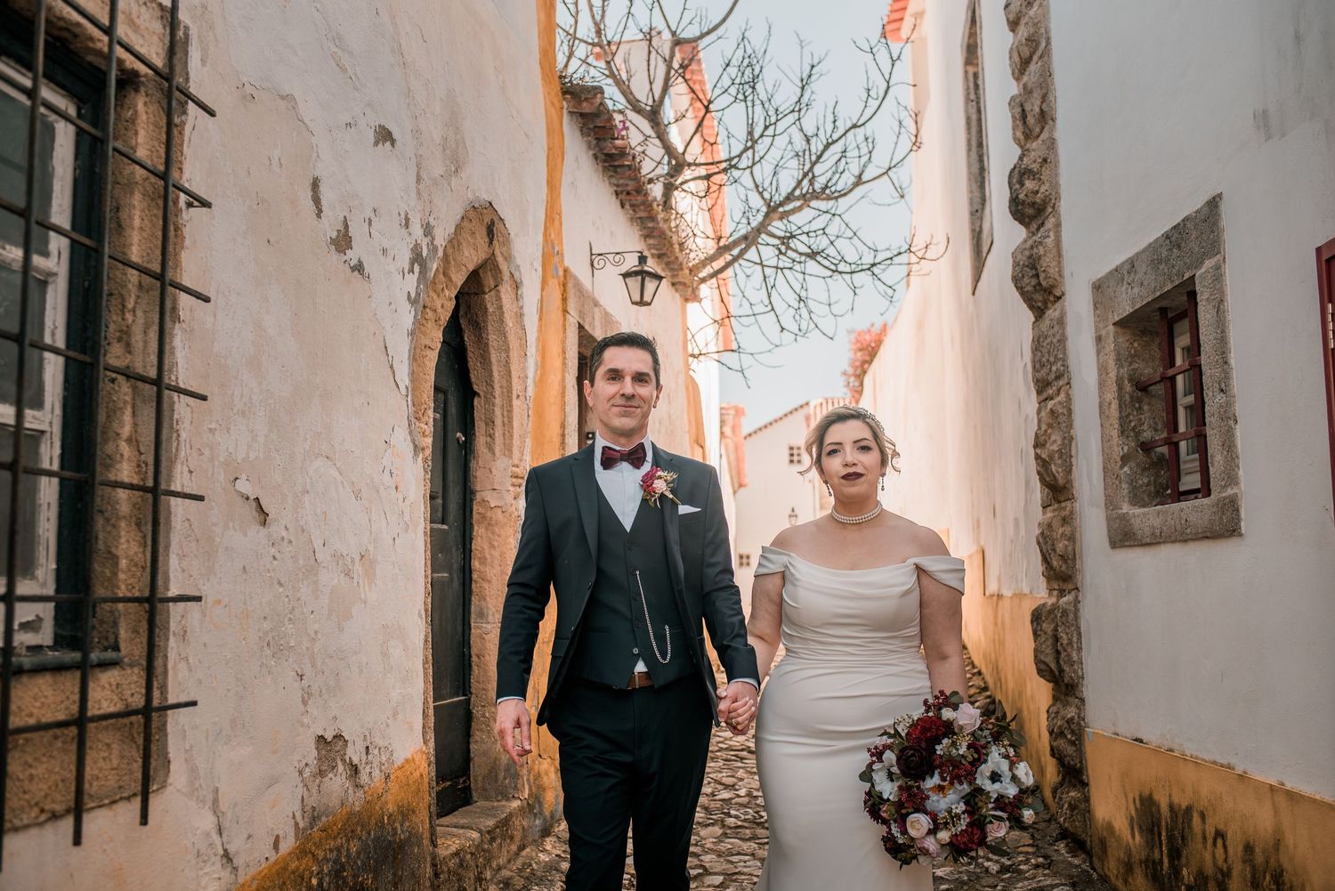 Bride and groom embracing in the historic streets of Óbidos during a destination wedding in Portugal.