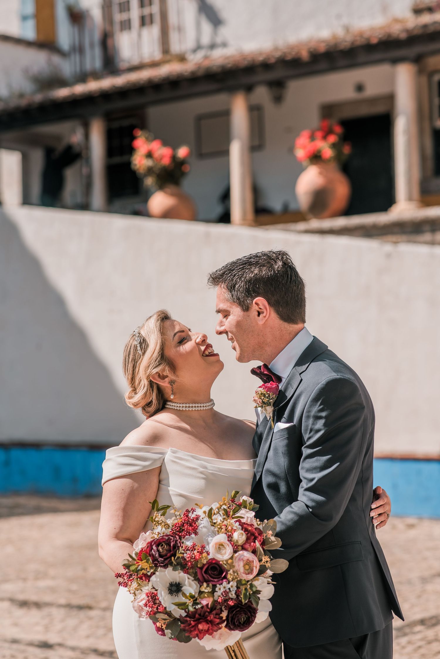 Bride and groom embracing in the historic streets of Óbidos during a destination wedding in Portugal.