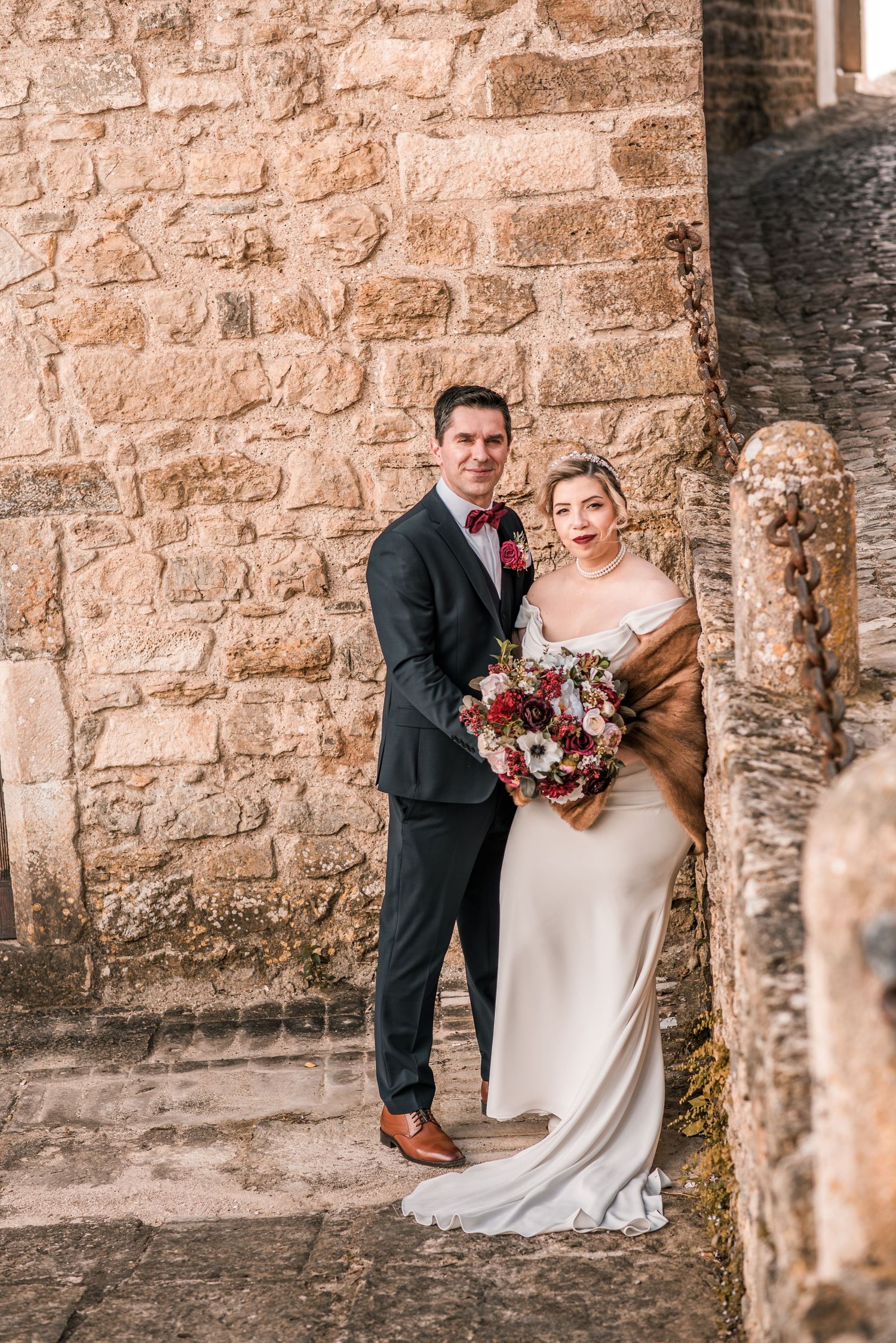 Intimate destination wedding in Óbidos, Portugal, with bride and groom walking through the medieval streets at sunset.
