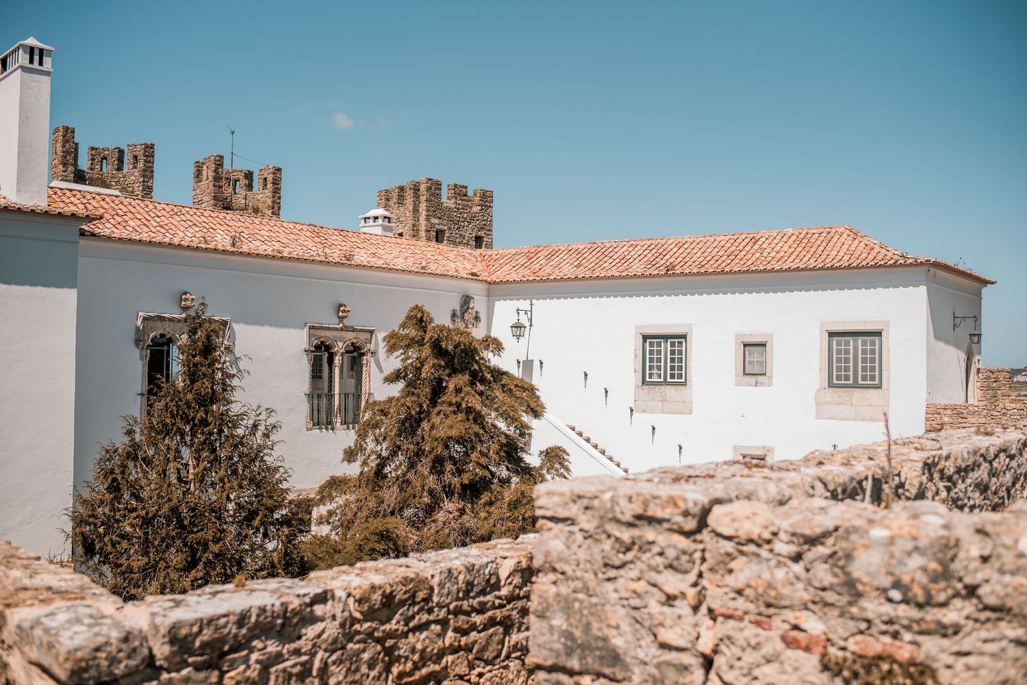 Intimate destination wedding in Óbidos, Portugal, with bride and groom walking through the medieval streets at sunset.