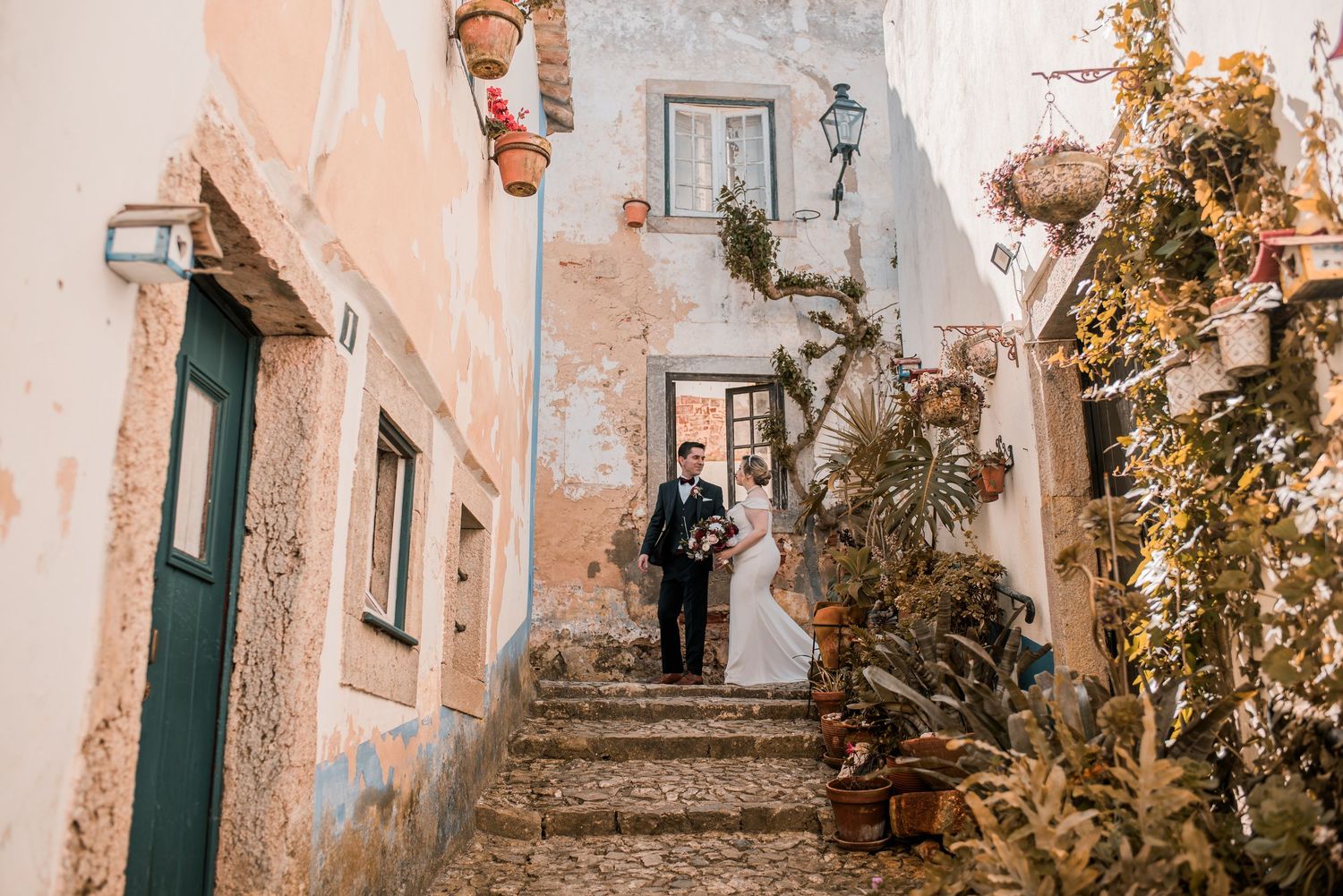 Bride and groom embracing in the historic streets of Óbidos during a destination wedding in Portugal.