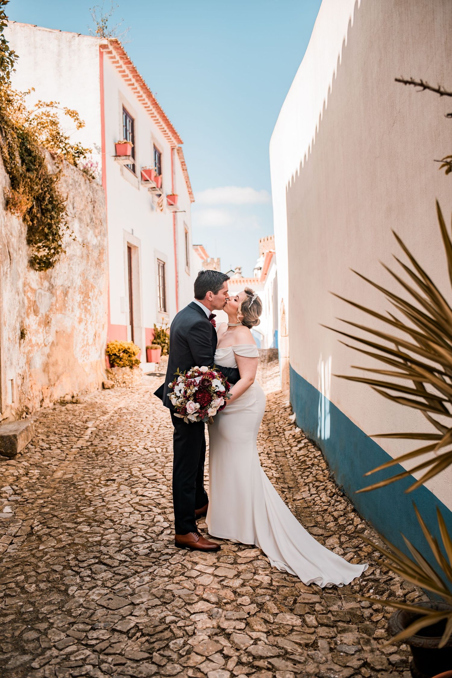 Bride and groom embracing in the historic streets of Óbidos during a destination wedding in Portugal.