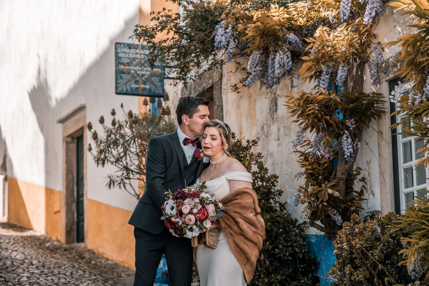 Intimate destination wedding in Óbidos, Portugal, with bride and groom walking through the medieval streets at sunset.