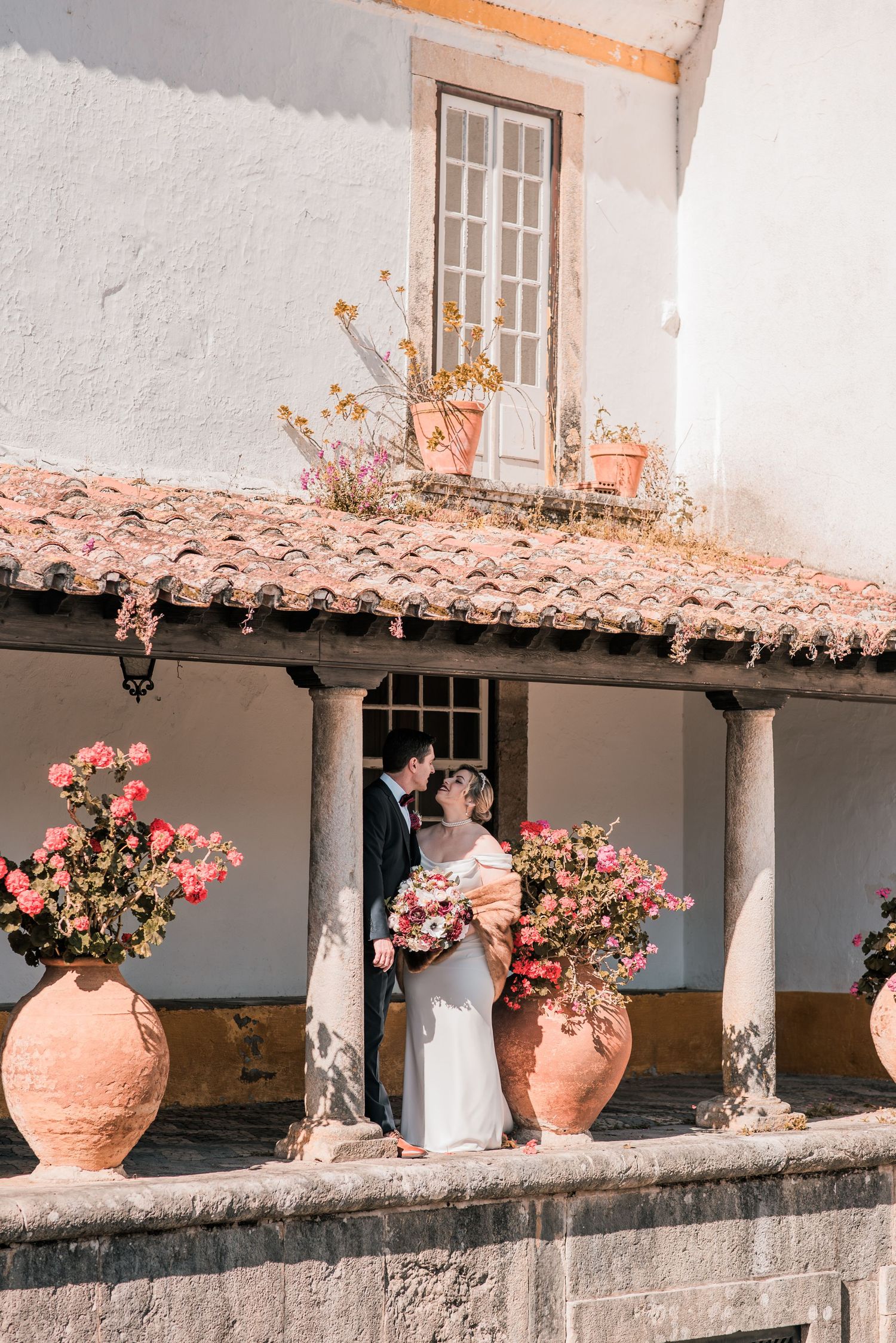 Intimate destination wedding in Óbidos, Portugal, with bride and groom walking through the medieval streets at sunset.