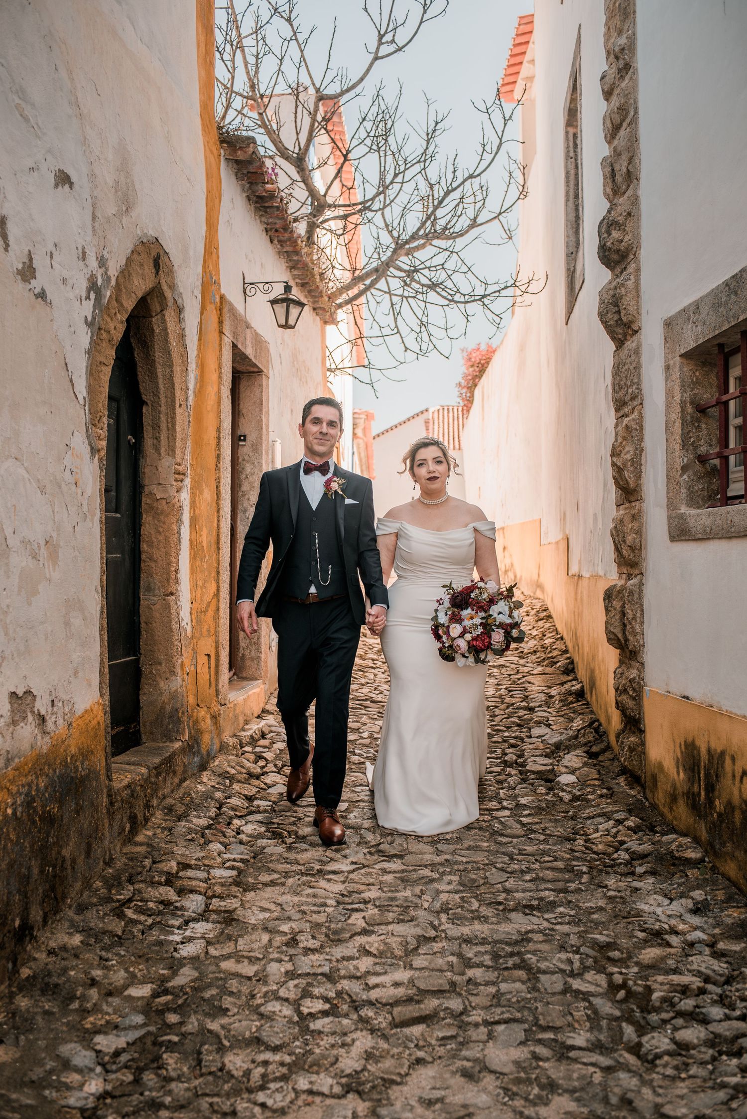 Bride and groom embracing in the historic streets of Óbidos during a destination wedding in Portugal.