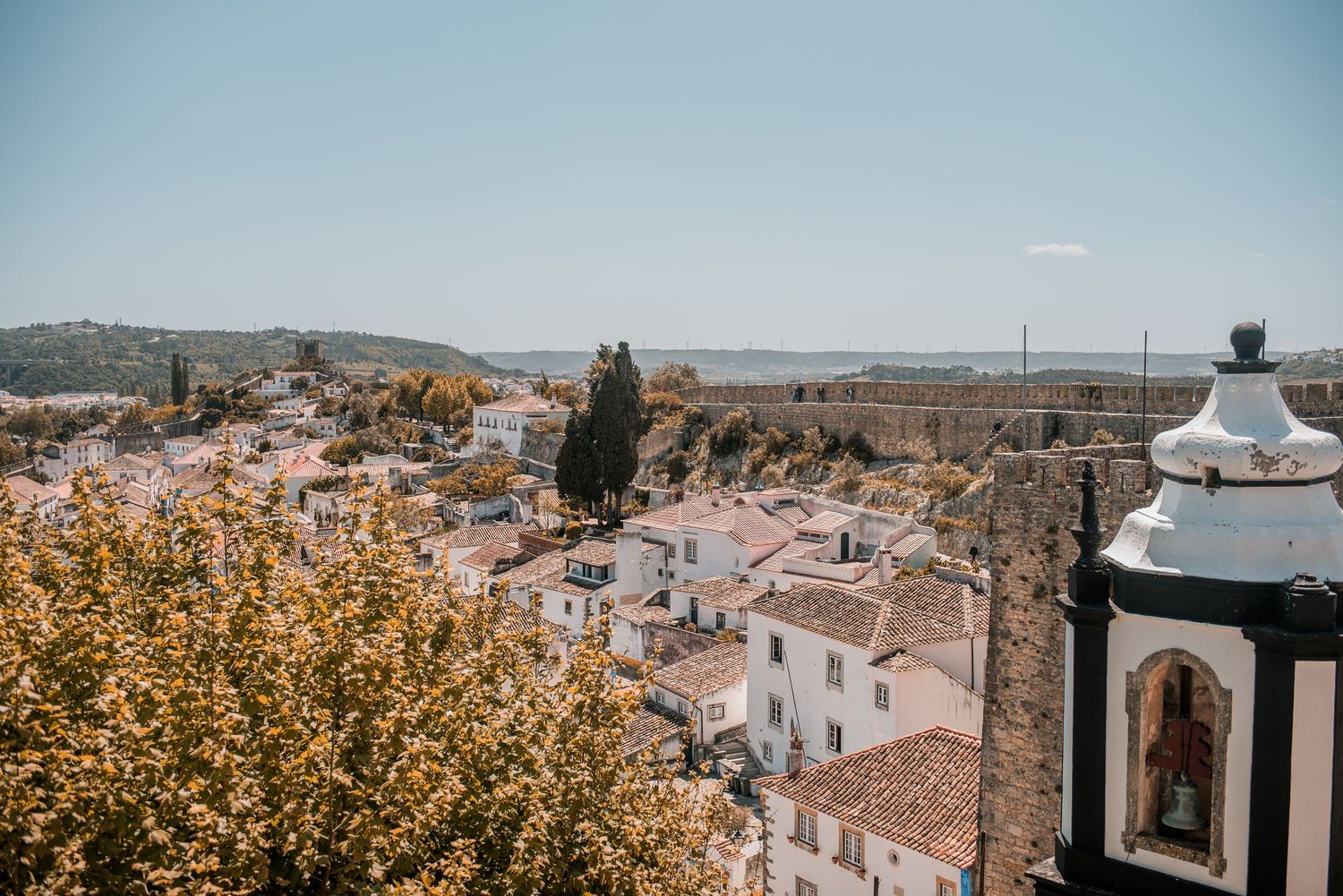 Intimate destination wedding in Óbidos, Portugal, with bride and groom walking through the medieval streets at sunset.