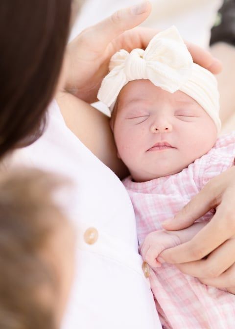 light and airy photo of mom and dad looking down at newborn baby girl cradled in mom's arms