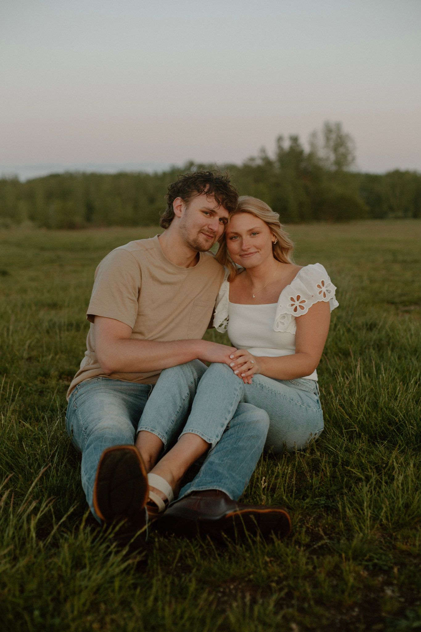 Couple sitting in a field during their engagement session at Millenium Park in Grand Rapids, MI.