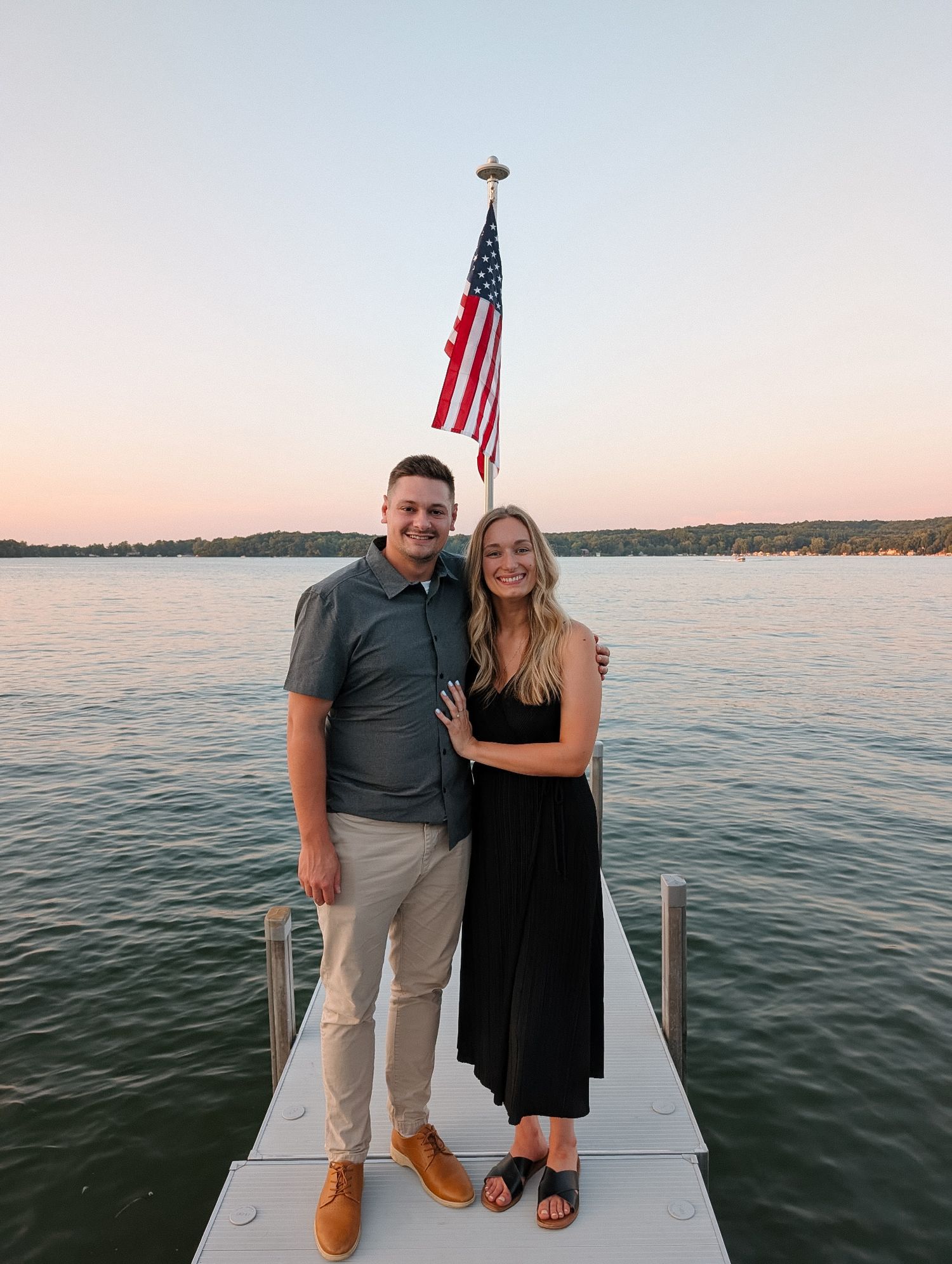 Eden and her husband Kyle standing on a dock in front of an American flag.