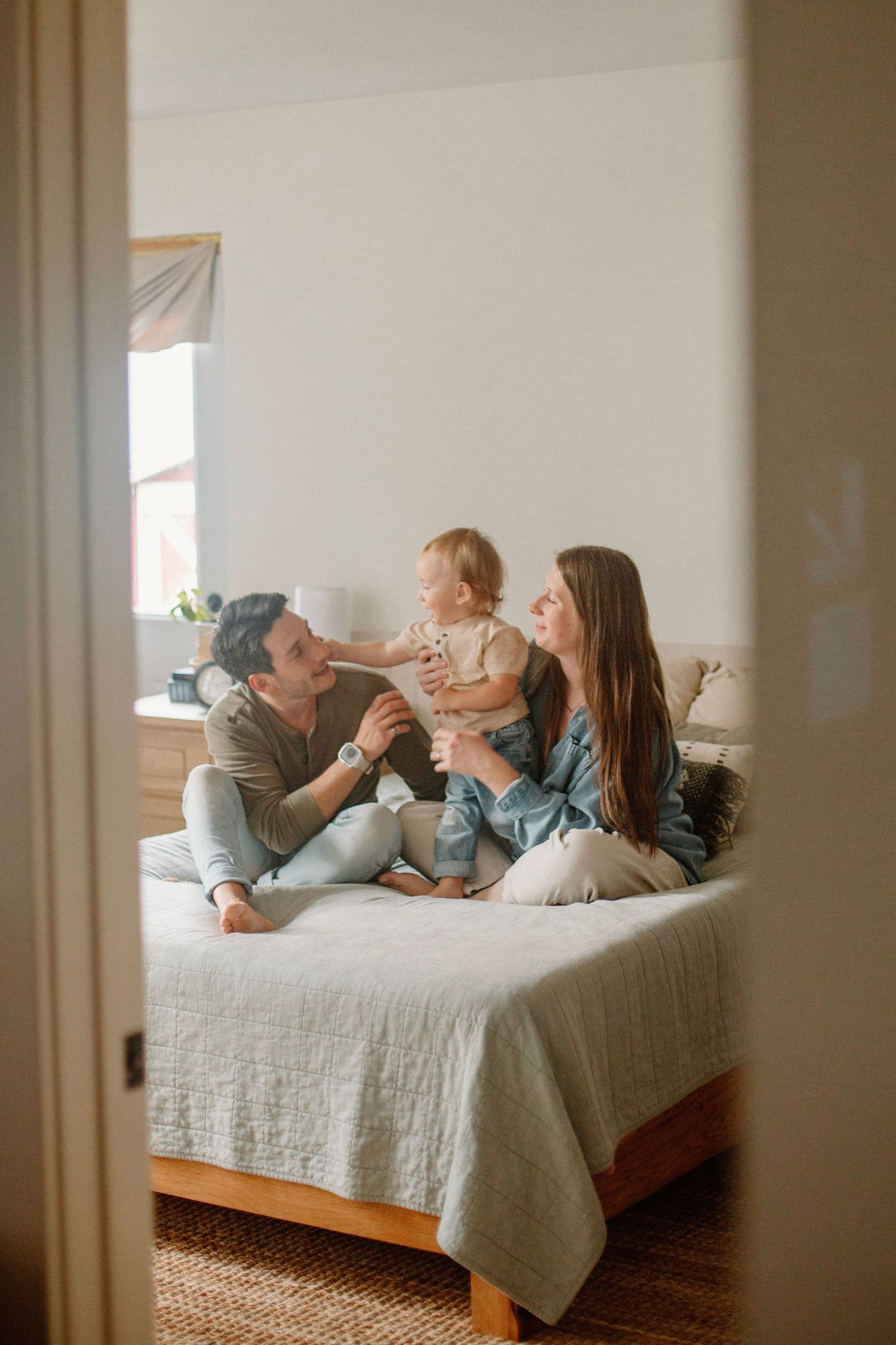 Family of three on their bed during their indoor lifestyle family session.