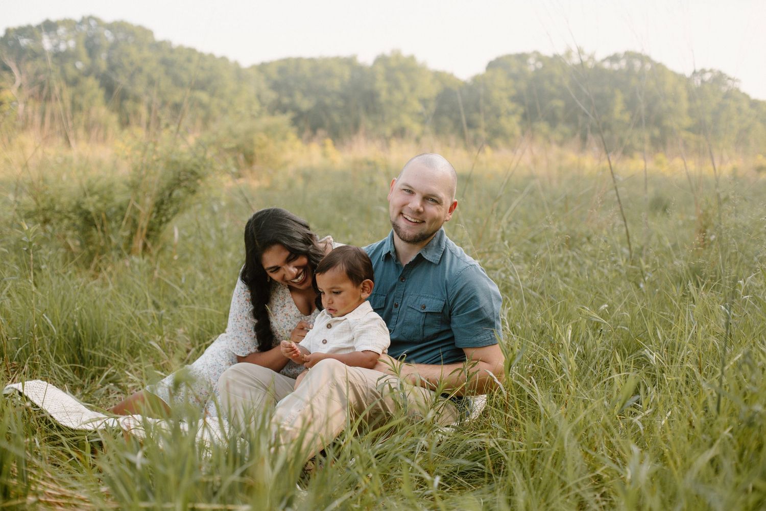 Family of three in a golden field during their outdoor family session at Grand Ravines Park.