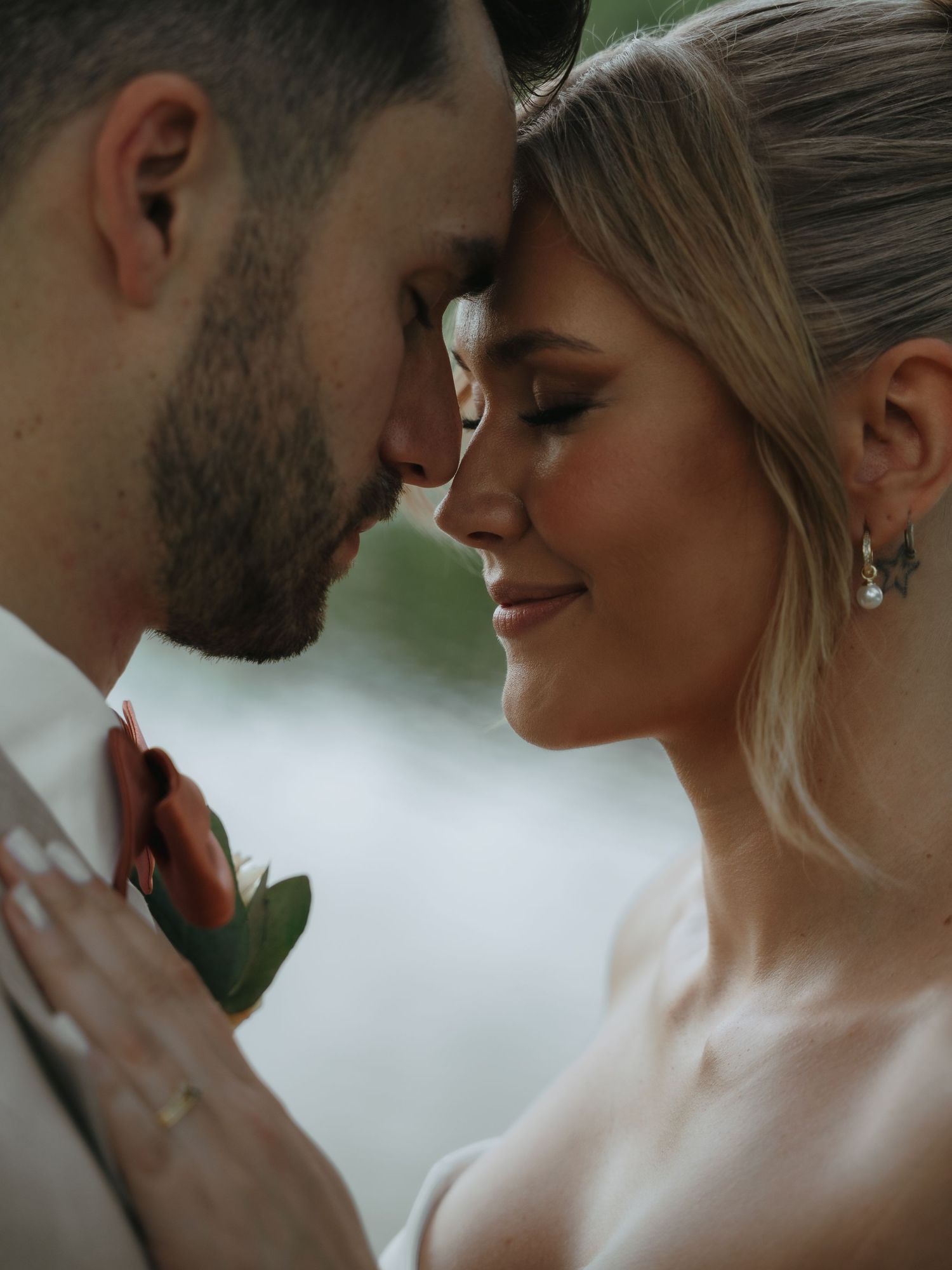 Intimate close-up romantic portrait of newlywed couple sharing tender moment with foreheads touching on their wedding day.