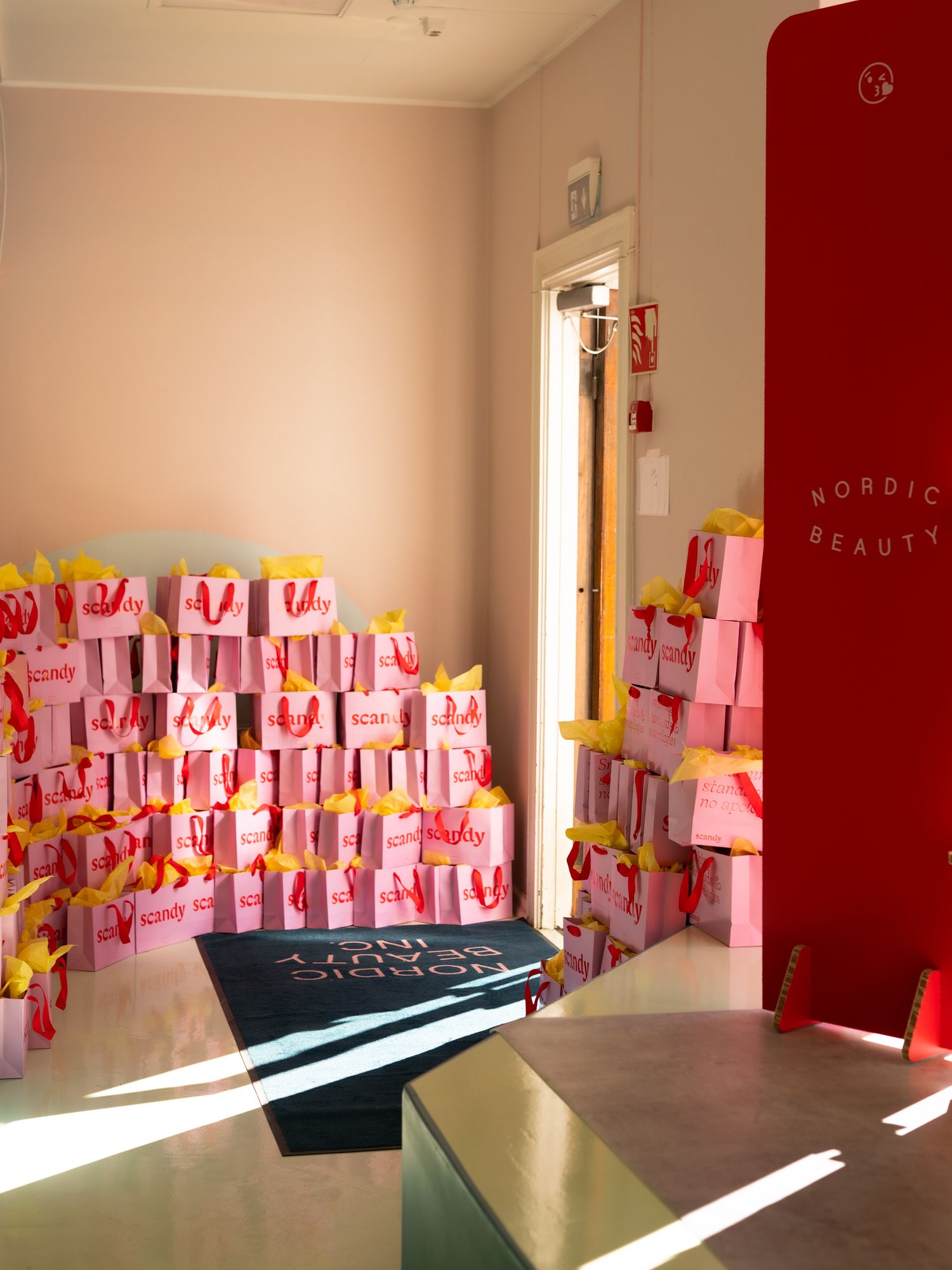 Pink McDonald's takeout bags arranged on display with sunlight streaming through window at a beauty retail location.