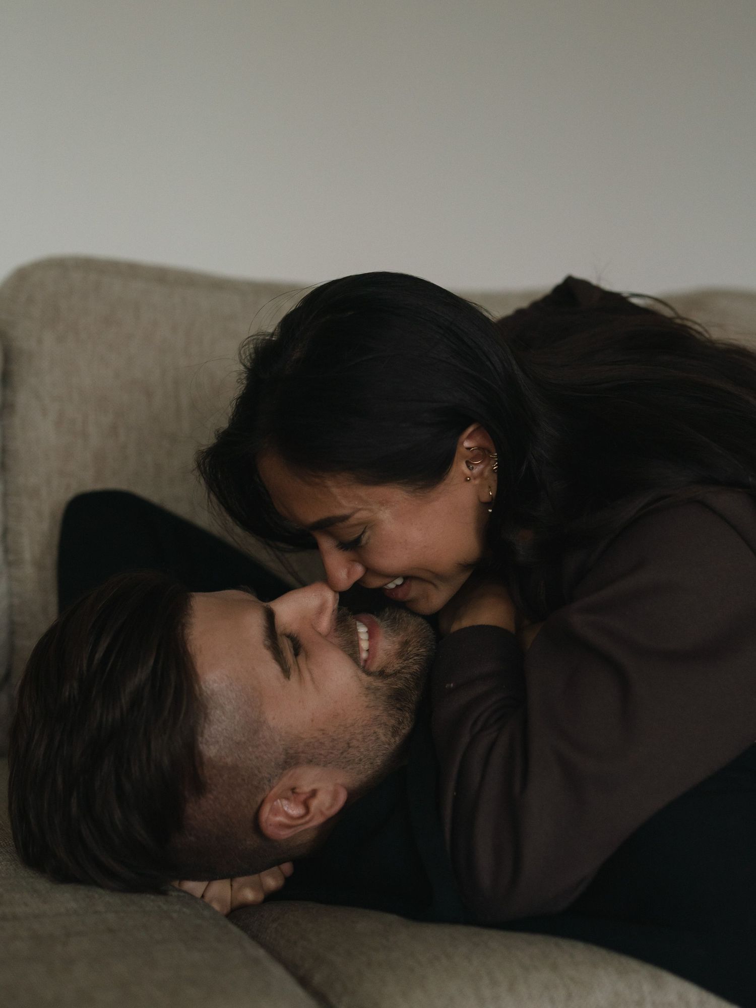 A tender intimate moment between two people lying on a couch sharing an affectionate embrace.