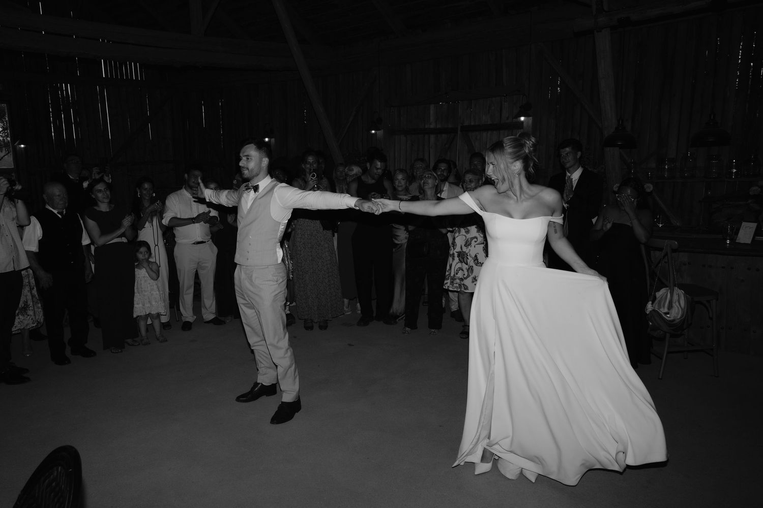 A couple performs an elegant dance move at a formal event as guests watch in the background.